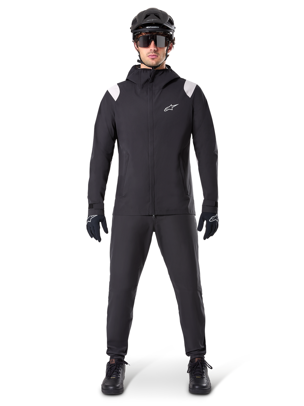 Alpinestars A-Dura regnjacka, regnjacka för mountainbike, svart med vita axeldetaljer och vit logotyp på bröstet, bärs med svarta byxor, svart hjälm, solglasögon och handskar, matchande mountainbike-utrustning för vått väder