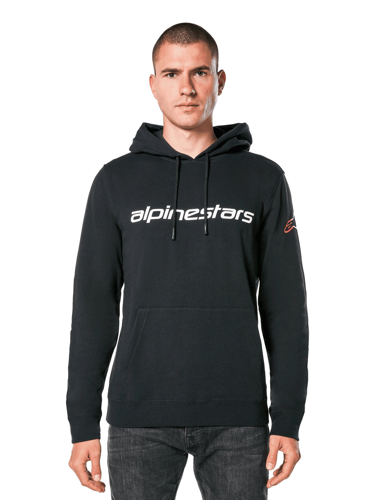Alpinestars Linear Wordmark V3 Hoodie, svart huvtröja i pullover-modell, vit Alpinestars-logotyp på bröstet, röd Ageless-logotyp på ärmen, känguruficka fram, huva med dragsko, bärs av en manlig modell, avslappnad motorsportinspirerad streetwear