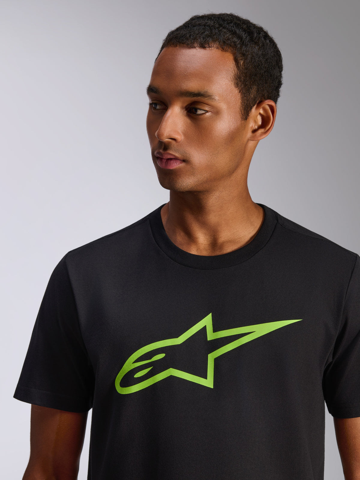 Alpinestars Ageless 2.0 CSF Tee, kortärmad t-shirt, svart med limegrön Alpinestars-stjärnlogotyp, bärs av en manlig modell, avslappnad motorsportinspirerad streetwear