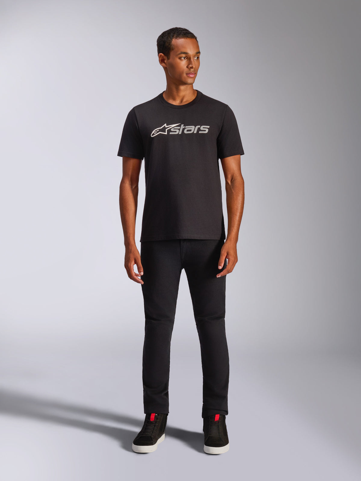 Alpinestars Blaze 2.0 CSF Tee, kortärmad t-shirt, svart med grå och vit logotyp på framsidan, bärs av modell med svarta byxor och svarta skor, avslappnad motorsportinspirerad streetwear