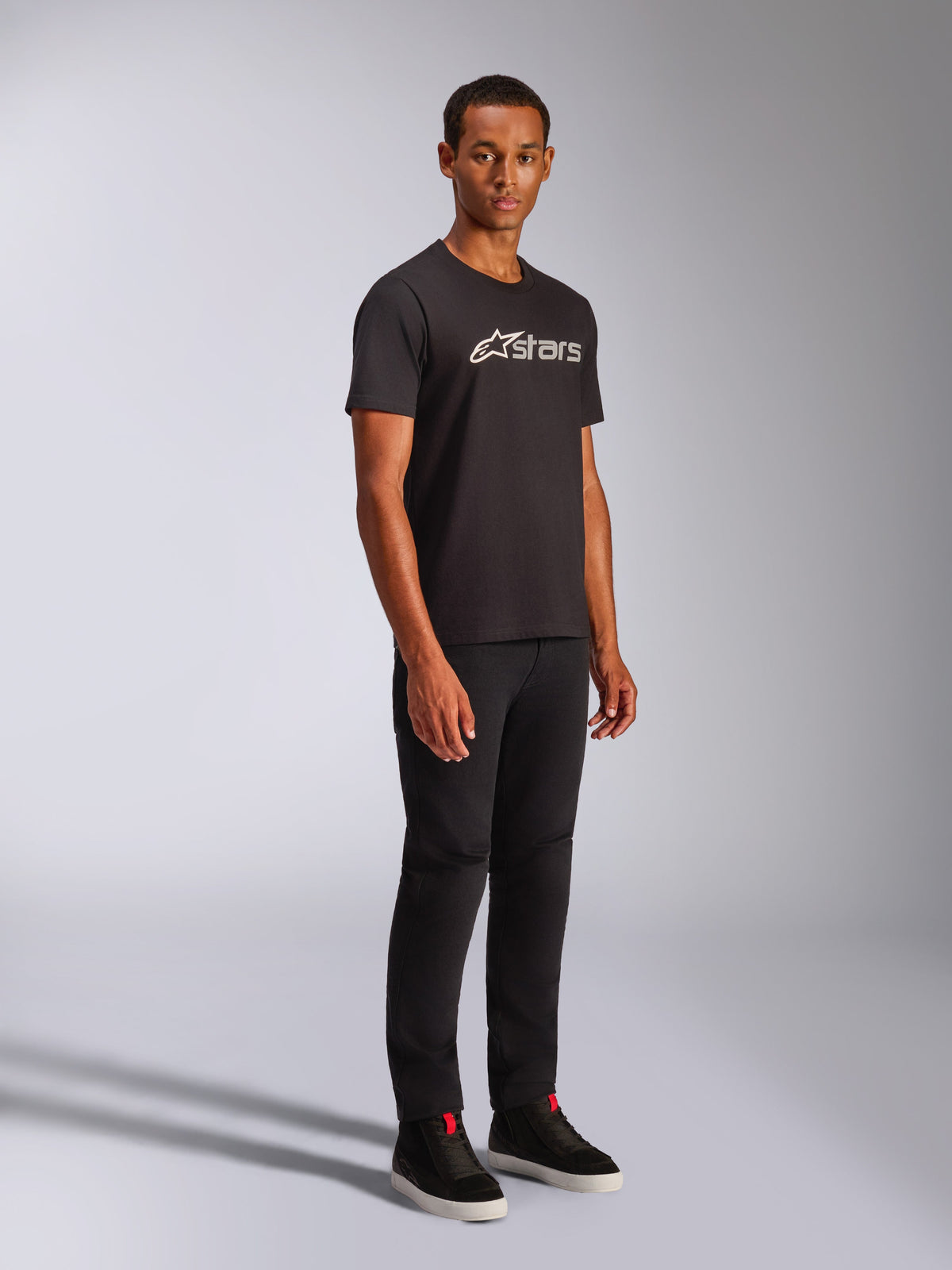 Alpinestars Blaze 2.0 CSF T-shirt, kortärmad T-shirt, svart med vit och grå logografik, bärs av en manlig modell med svarta byxor och high-top sneakers, casual motorsport-streetwear