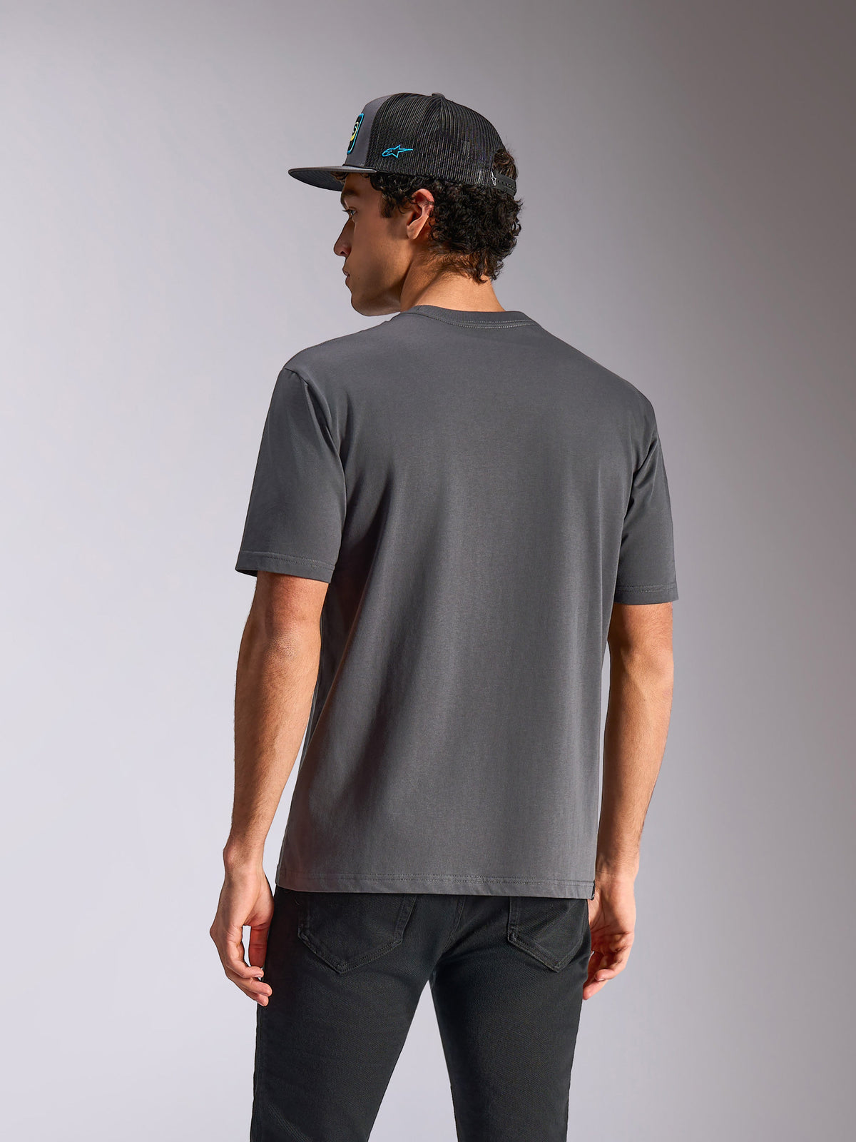 Alpinestars Blaze 2.0 CSF Tee, kortärmad t-shirt, mörkgrå, baksida, bärs med svarta jeans och en nätkeps, avslappnad motorsportinspirerad streetwear