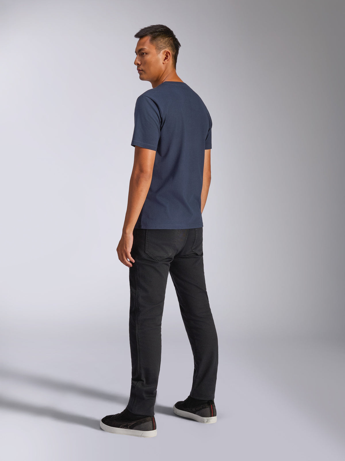 Alpinestars Blaze 2.0 CSF Tee, kortärmad t-shirt, mörkblå, vy bakifrån på modell, kombinerad med svarta byxor och sneakers, avslappnad motorsportinspirerad streetwear