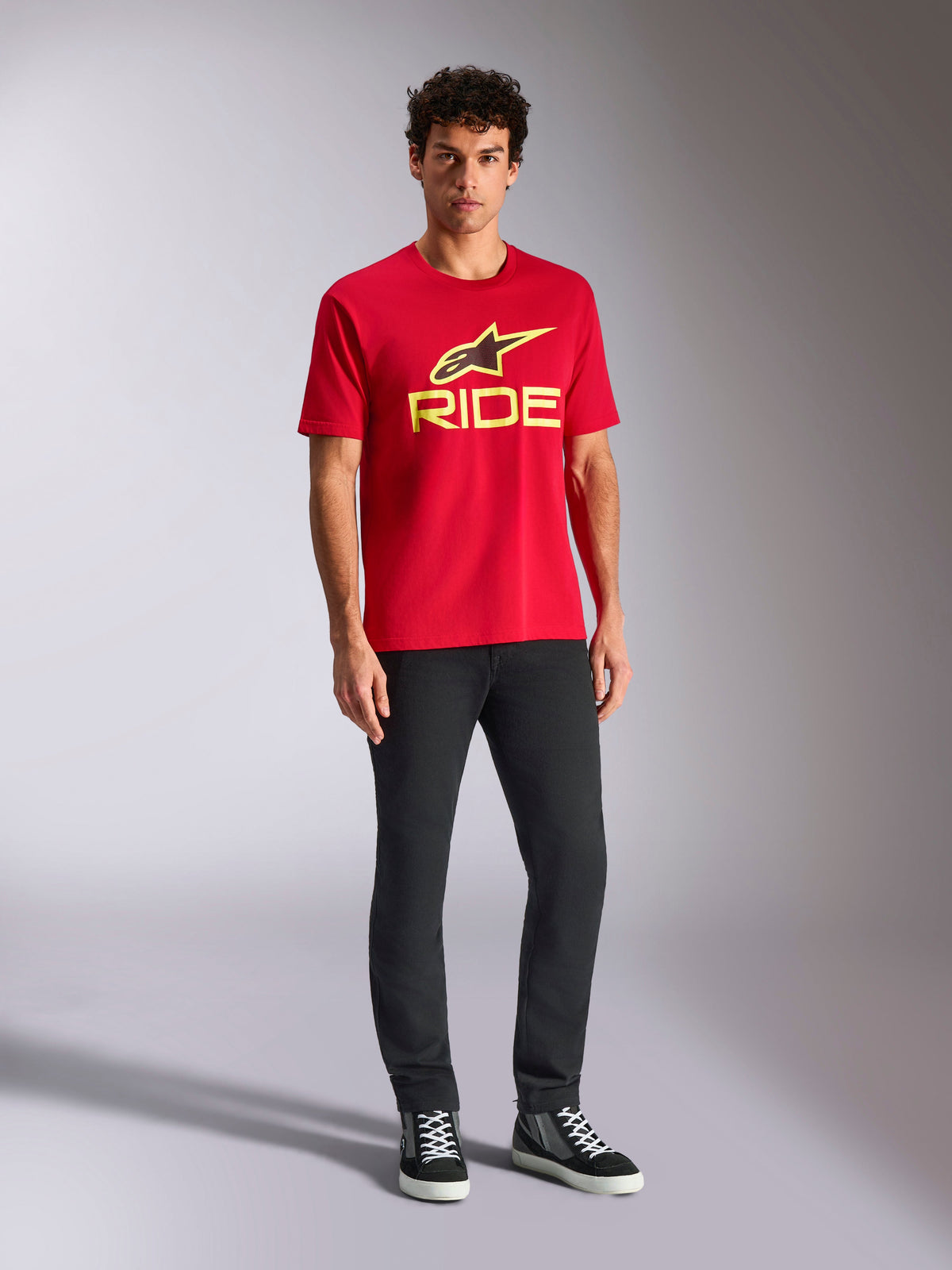 Alpinestars Ride 4.0 CSF Tee, kortärmad t-shirt, röd med varselgul Alpinestars-stjärna och Ride-logotyp, bärs av modell med svarta byxor och sneakers, avslappnade motorsportkläder