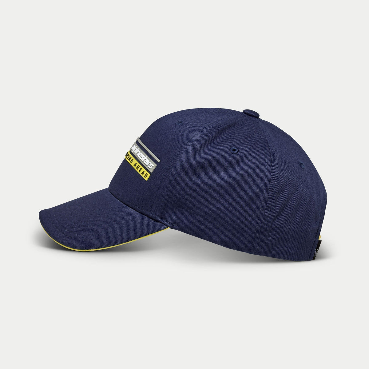 Alpinestars Par Hat, mörkblå baseballkeps, sidovy, strukturerad krona med böjd skärm och gul sandwich-detalj, Alpinestars Racing Ahead linjärt logotypbroderi i 3D, avslappnad motorsport-inspirerad huvudbonad