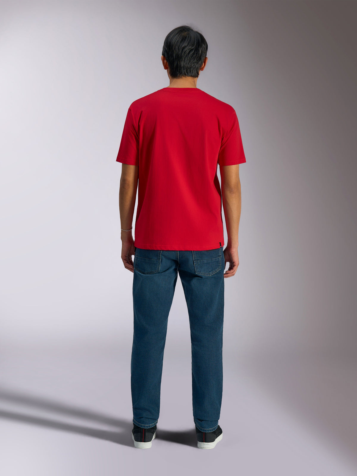 Alpinestars Ageless Shadow CSF Tee, back view of red short sleeve t-shirt, worn with dark blue denim jeans and black sneakers, casual motorsport streetwear