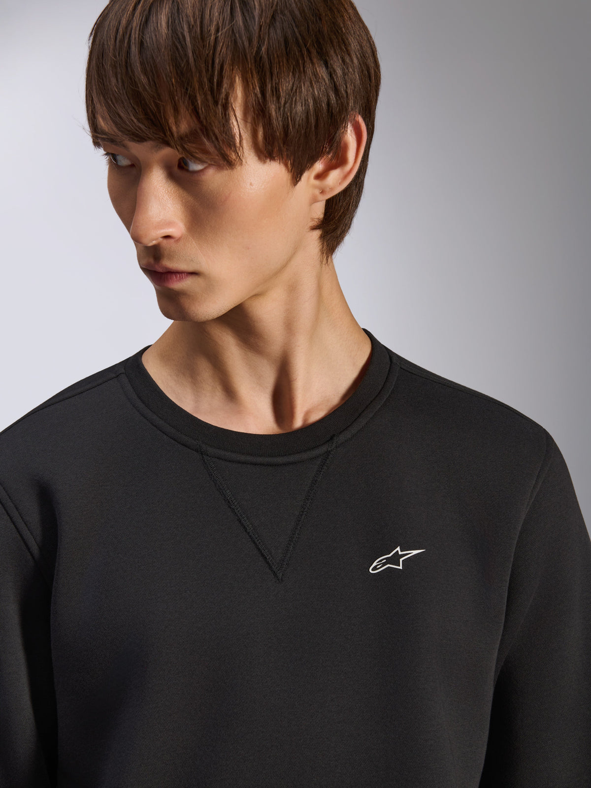 Alpinestars Positive Crew sweatshirt, svart rundhalsad tröja med V-sömsdetalj vid halsen, liten vit Alpinestars-logotyp på vänster bröst, avslappnad motorsportinspirerad streetwear
