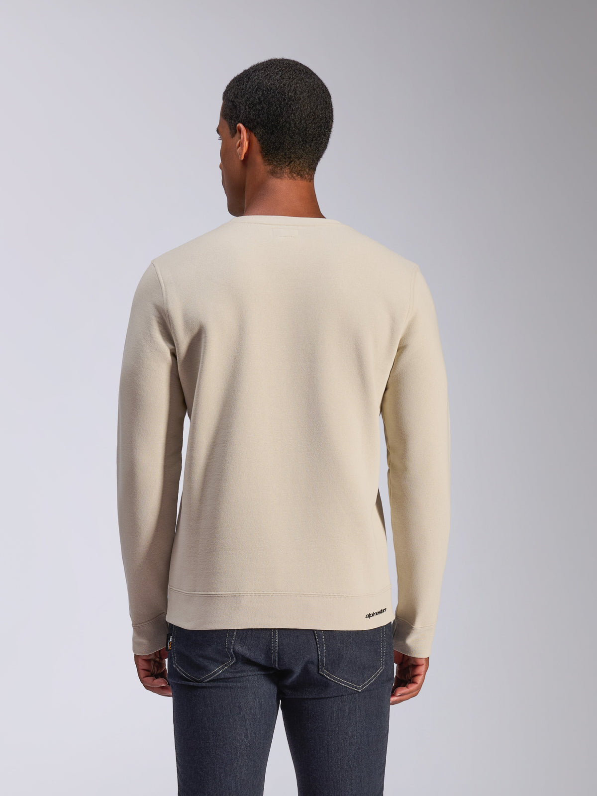 Alpinestars Positive Crew, Off White sweatshirt med rund hals, sedd bakifrån, casual motorsport-streetwear, ribbad fåll och muddar, med en liten Alpinestars-logotyp på den bakre fållen