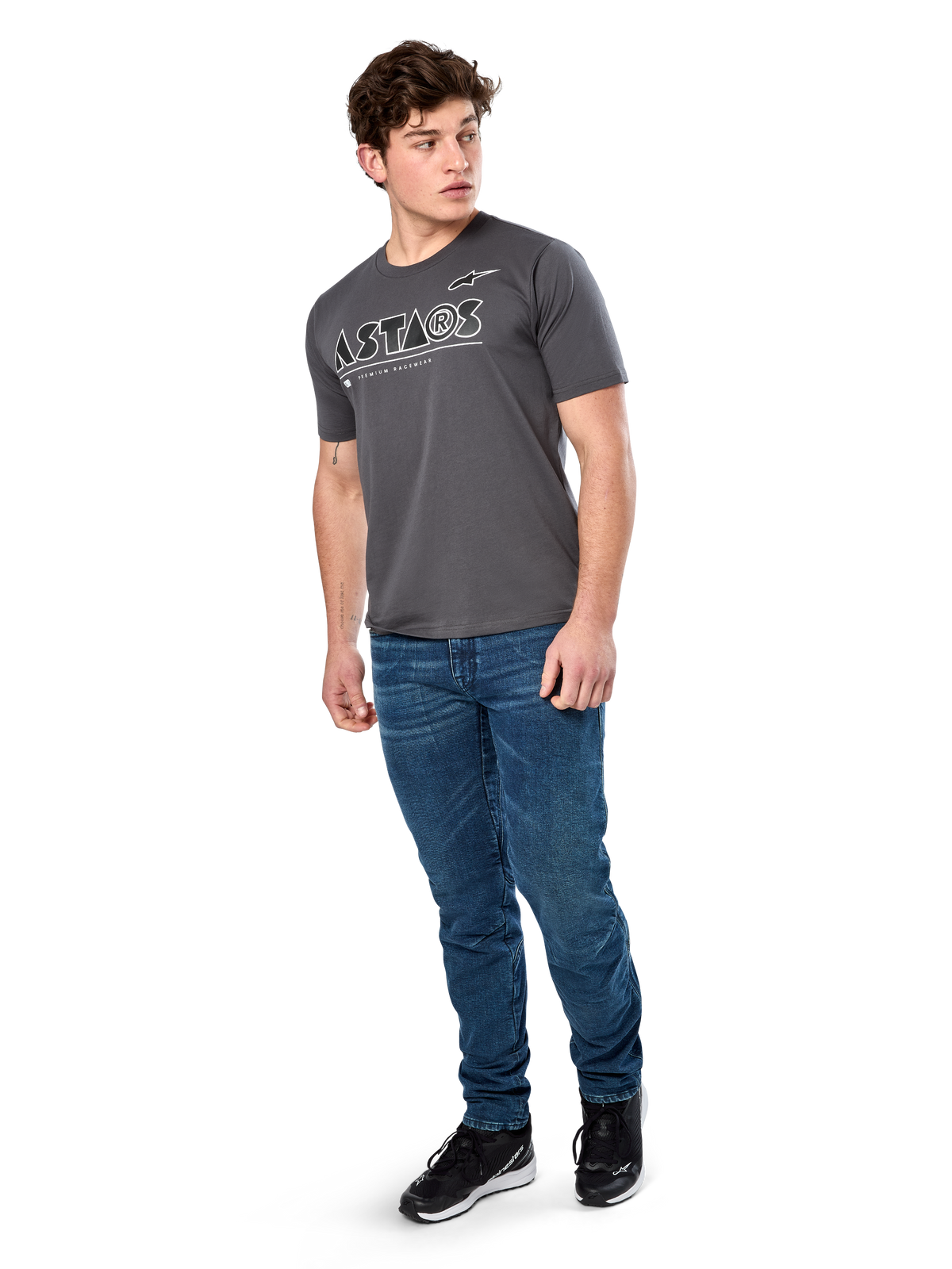 Alpinestars Cereal CSF T-shirt, kortärmad t-shirt, mörkgrå, vit geometrisk Astars-textlogotyp, casual motorsport-streetwear bärs med blå jeans och svarta sneakers