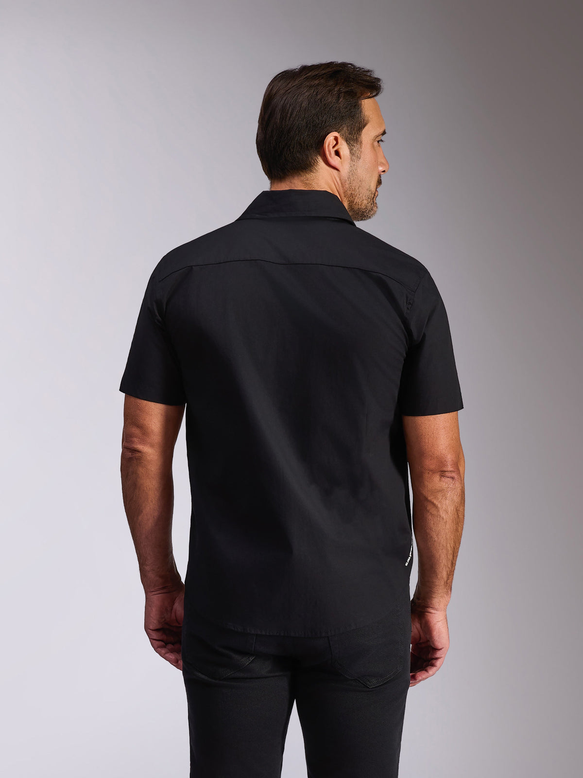 Alpinestars Strive Woven Shirt, svart kortärmad skjorta, vy bakifrån som visar ryggok och skräddarsydd passform, avslappnad motorsportinspirerad streetwear