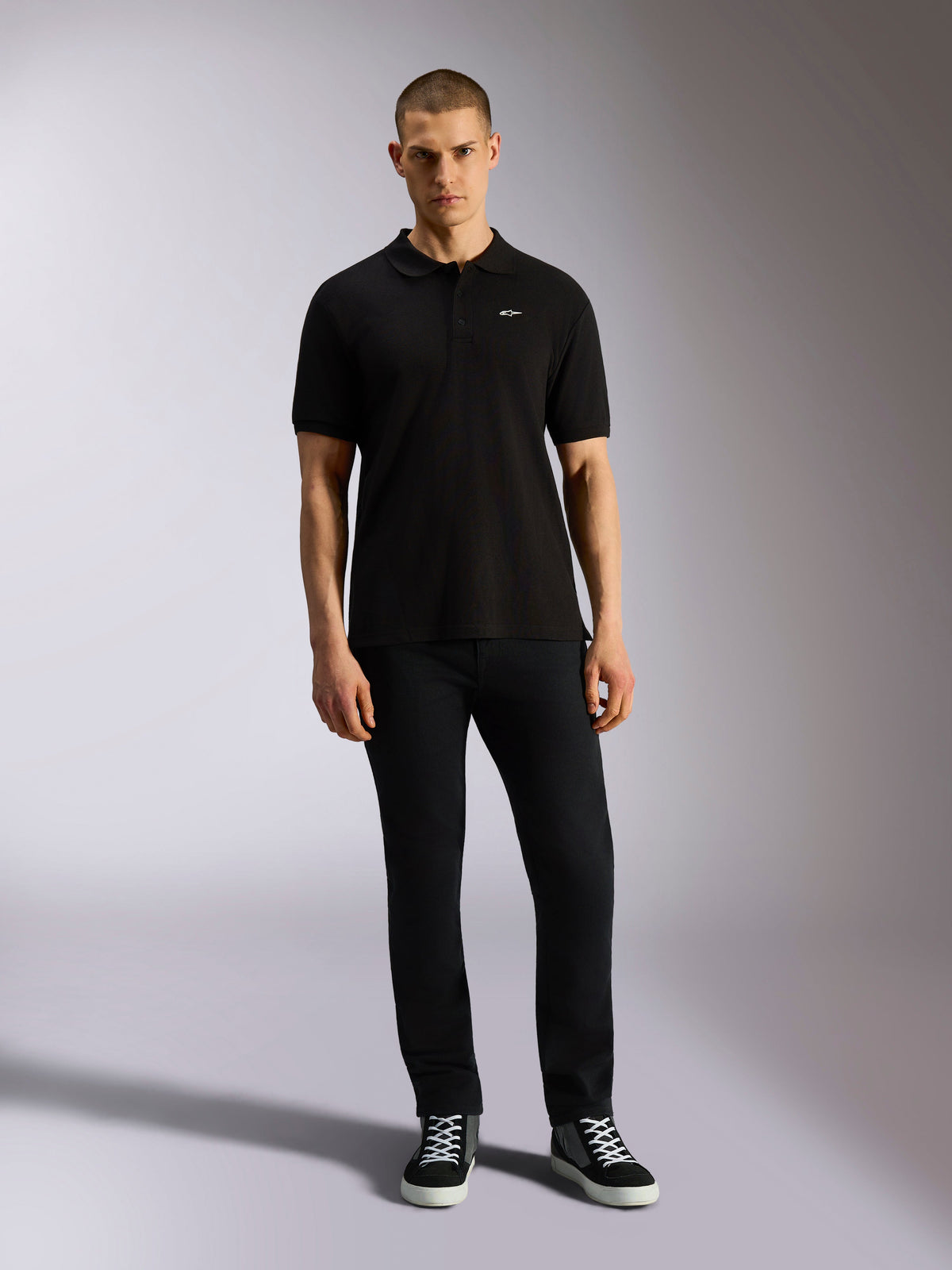 Alpinestars Endeavor Classic Polo, Short Sleeve Pique Polo Shirt, Black, small white Astars logo on chest, ribbed collar and cuffs, worn by model with black pants and sneakers, casual motorsport streetwear