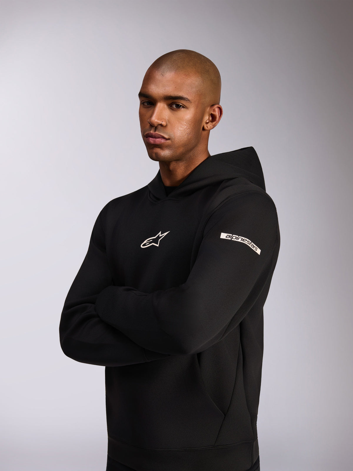 Alpinestars Insight Hoodie, casual sportswear hoodie, Black, white Astars logo on chest and word logo on the upper sleeve, model wearing hoodie with arms crossed, premium double face fleece construction