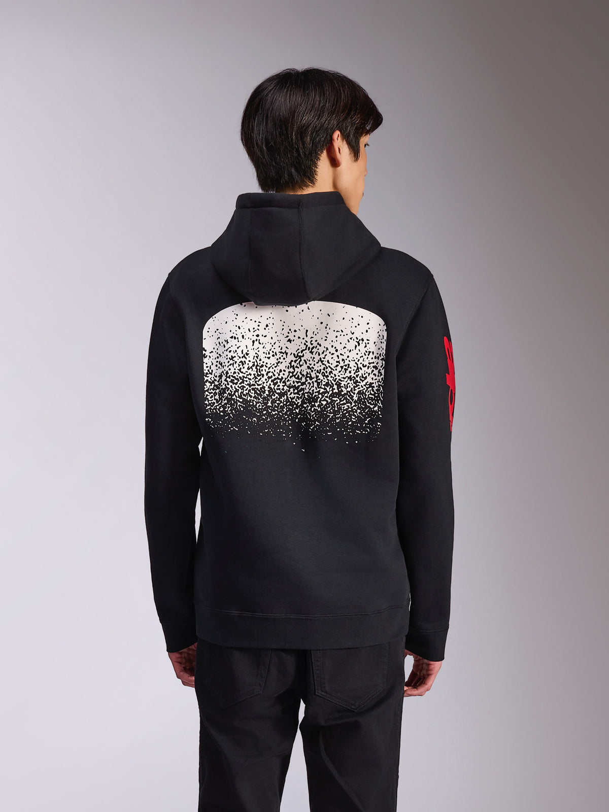 Alpinestars Obsessed Hoodie, baksida av svart huvtröja i fleece, med en stor vit spräcklig MX-graderingsgrafik på ryggen och röda Alpinestars-logotyper på ärmarna, avslappnat motorsportinspirerat streetwear