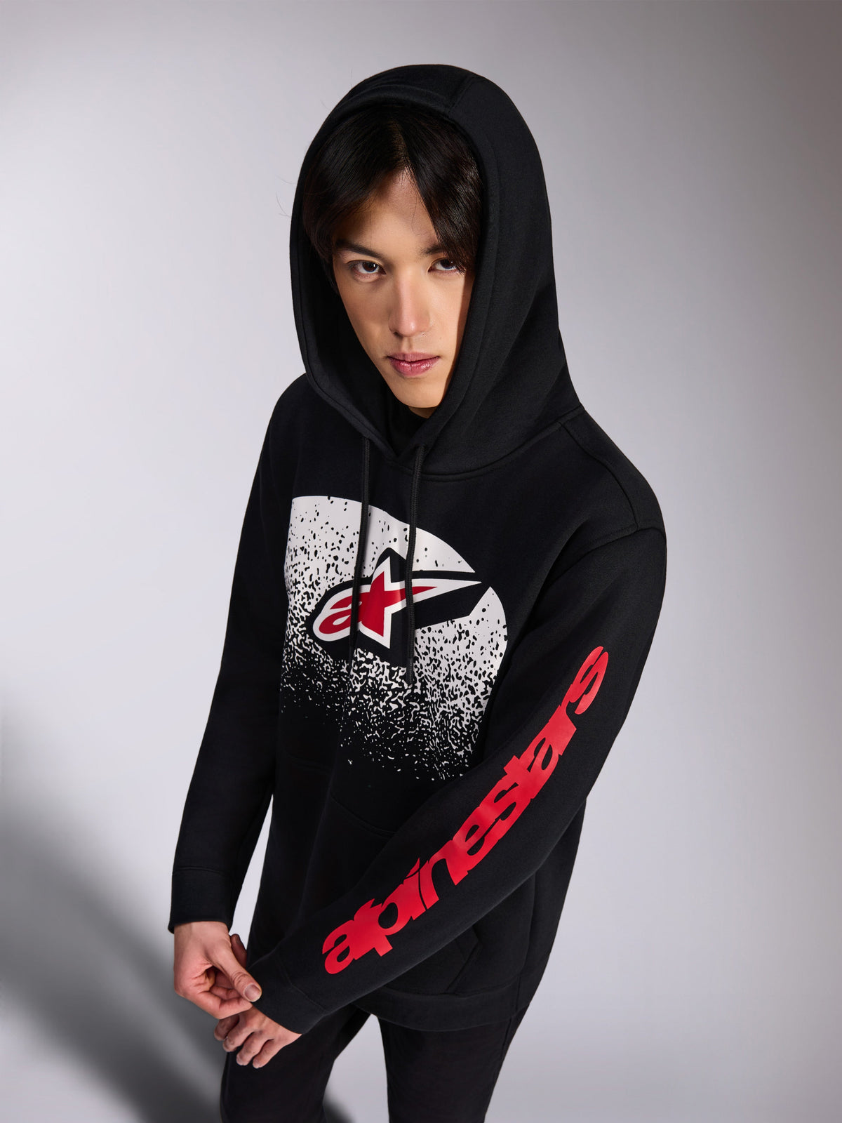 Alpinestars Obsessed Hoodie, svart huvtröja i fleece, röd och vit Astars-logotyp framtill med vit MX-gradering, röd Alpinestars-ordlogga på ärmen, huva med dragsnören, vardagligt motorsport-inspirerat streetwear