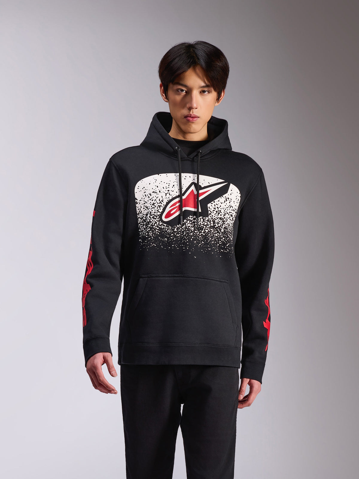 Alpinestars Obsessed Hoodie, sportiga vardagskläder, svart huvtröja med en stor Astars-logotyp framtill med en vit och svart spräcklig MX-gradering, rött tryck på ärmarna, huva med dragsnöre och ribbade muddar.