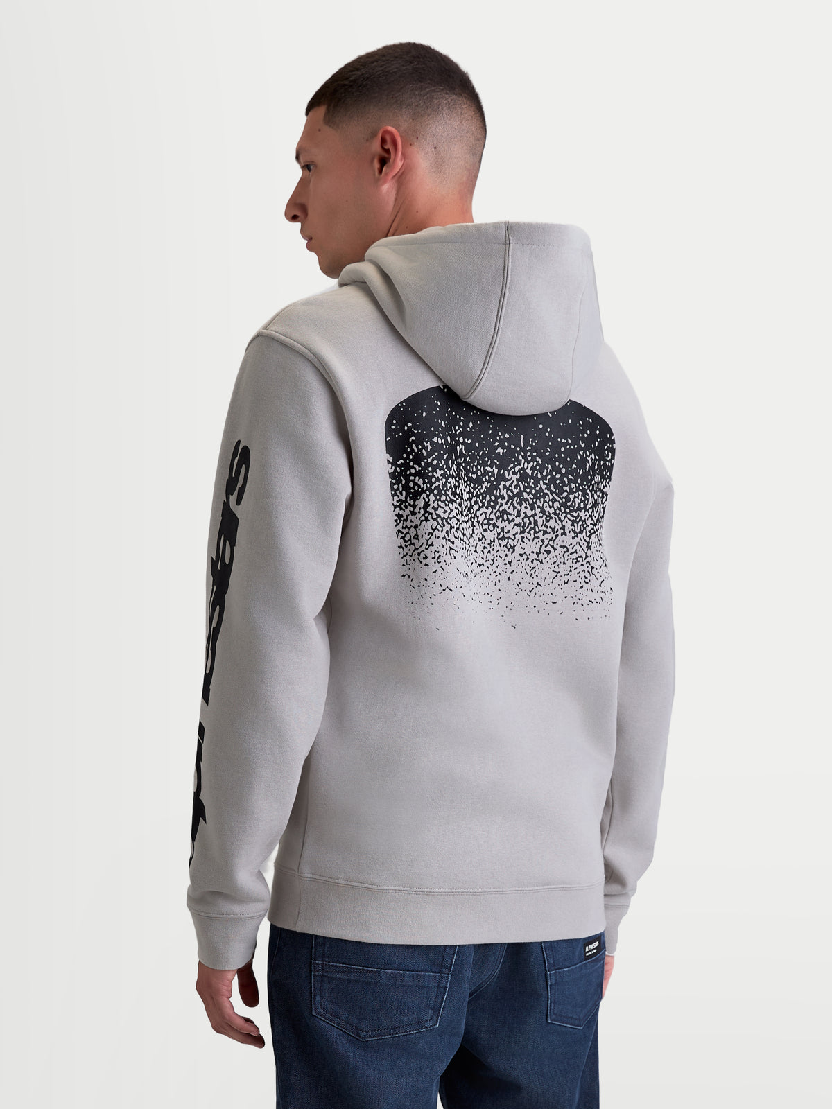 Alpinestars Obsessed huvtröja, cementgrå fleecepullover för herrar med stor svart MX-inspirerad gradientgrafik på ryggen och logotyper på ärmarna, ryggvy på modell, avslappnad motorsport-streetwear.