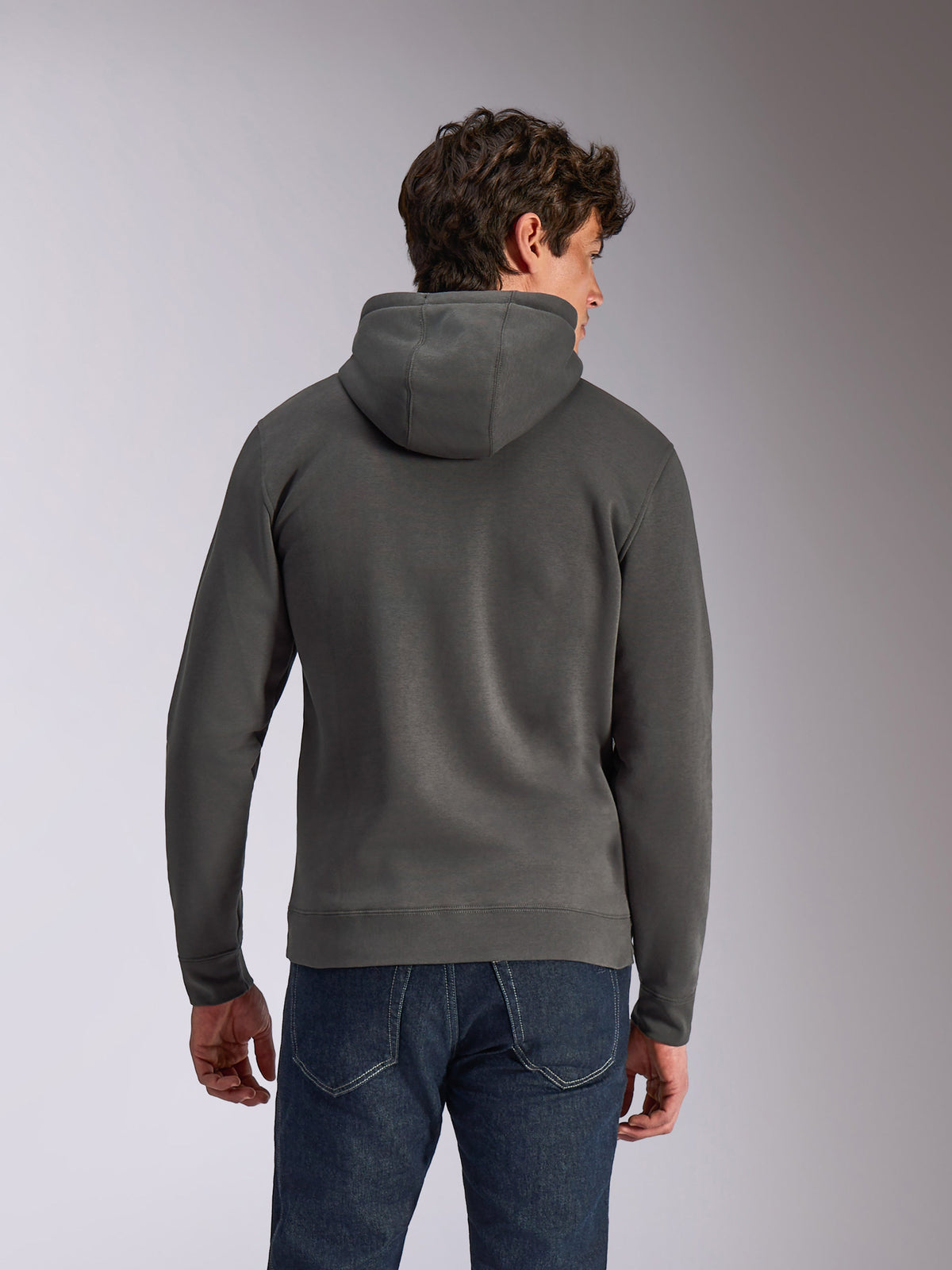 Alpinestars Ellipsoid Hoodie, Gunmetal-grå, vardagliga sportkläder, ryggvy av man som bär huvtröja i fleece, ribbad fåll och muddar, kombinerad med blå jeans