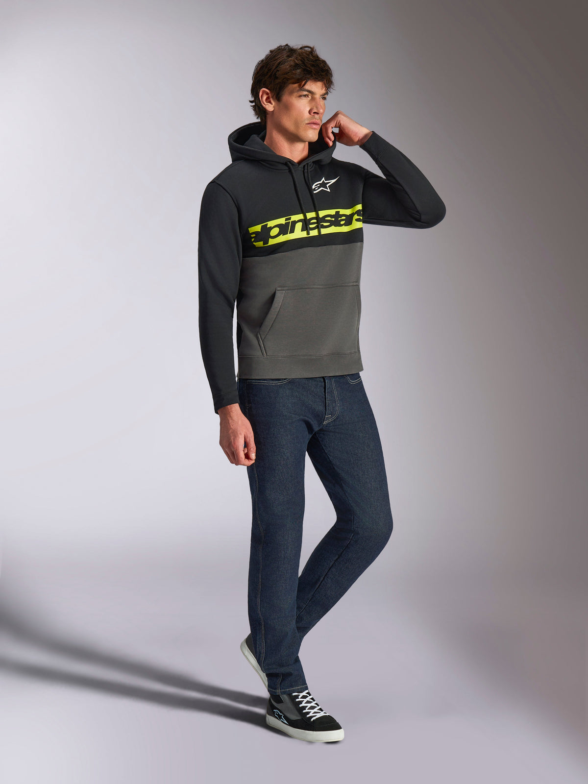 Alpinestars Parallel Huvtröja, vardaglig streetwear, färgblockerad i svart och gunmetal-grått, neongul Alpinestars ordlogotyp på bröstet, vit Astars-logotyp, huva med dragsko, bärs med mörka jeans och sneakers