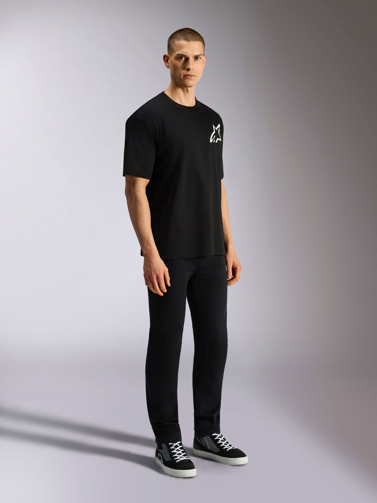 Alpinestars One Oversized CSF Tee, kortärmad t-shirt, svart, vit Astars-logotyp på bröstet, oversized passform, bärs av en manlig modell med svarta byxor och sneakers, avslappnad motorsport-inspirerad streetwear