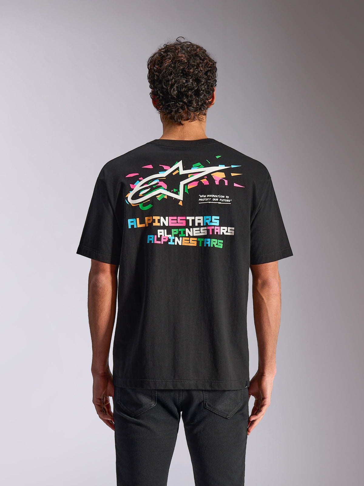 Alpinestars Wild Oversized CSF Tee, kortärmad t-shirt, svart, baksida med livfull flerfärgad Astars-logotyp och grafiska element, avslappnad motorsport-streetwear