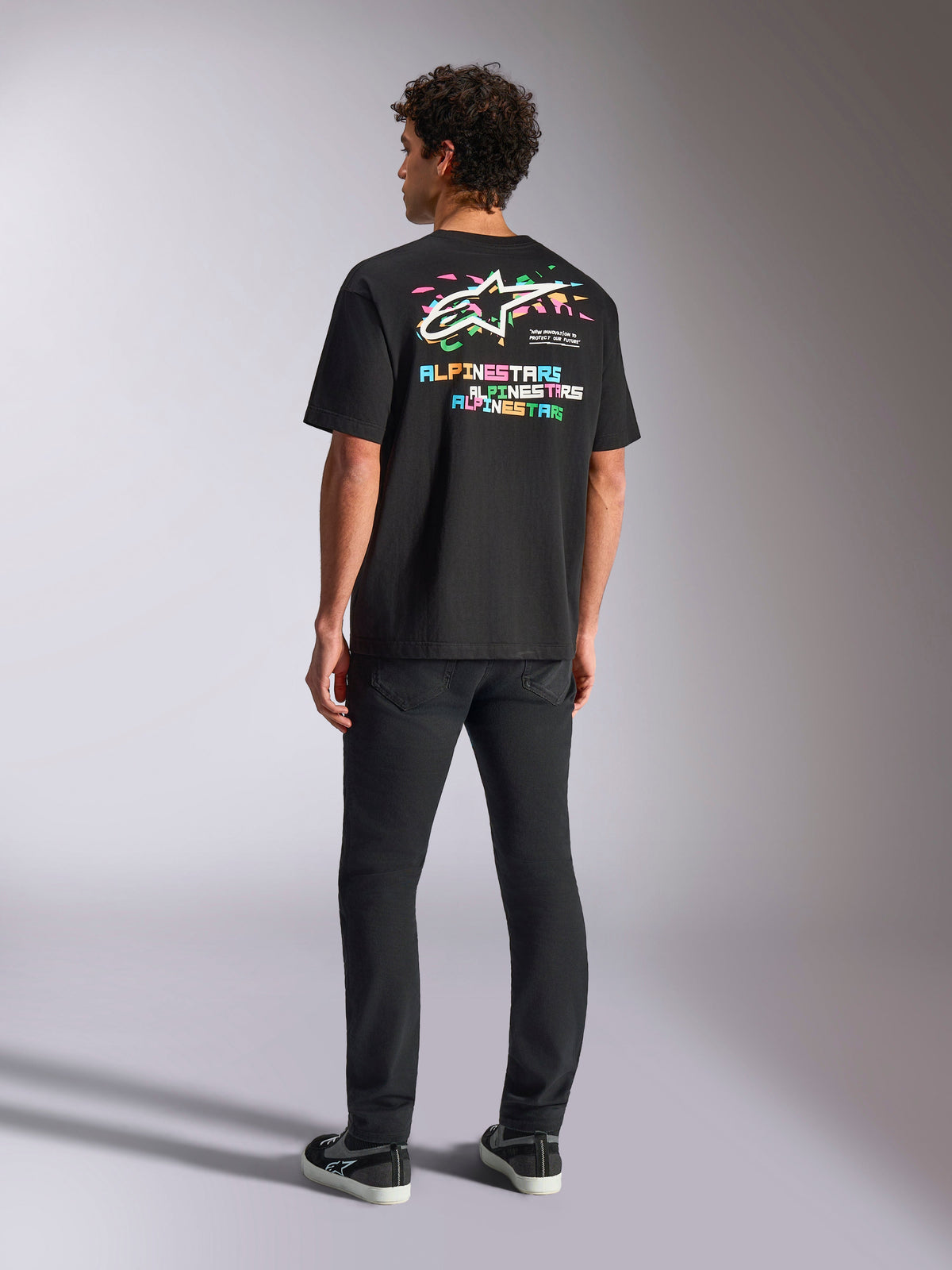 Alpinestars Wild Oversized CSF Tee, kortärmad t-shirt, svart, med en stor flerfärgad rygggrafik med Astars-logotyp och färgglad text, oversized passform, bärs med svarta slim-fit-byxor för en avslappnad streetwear-look
