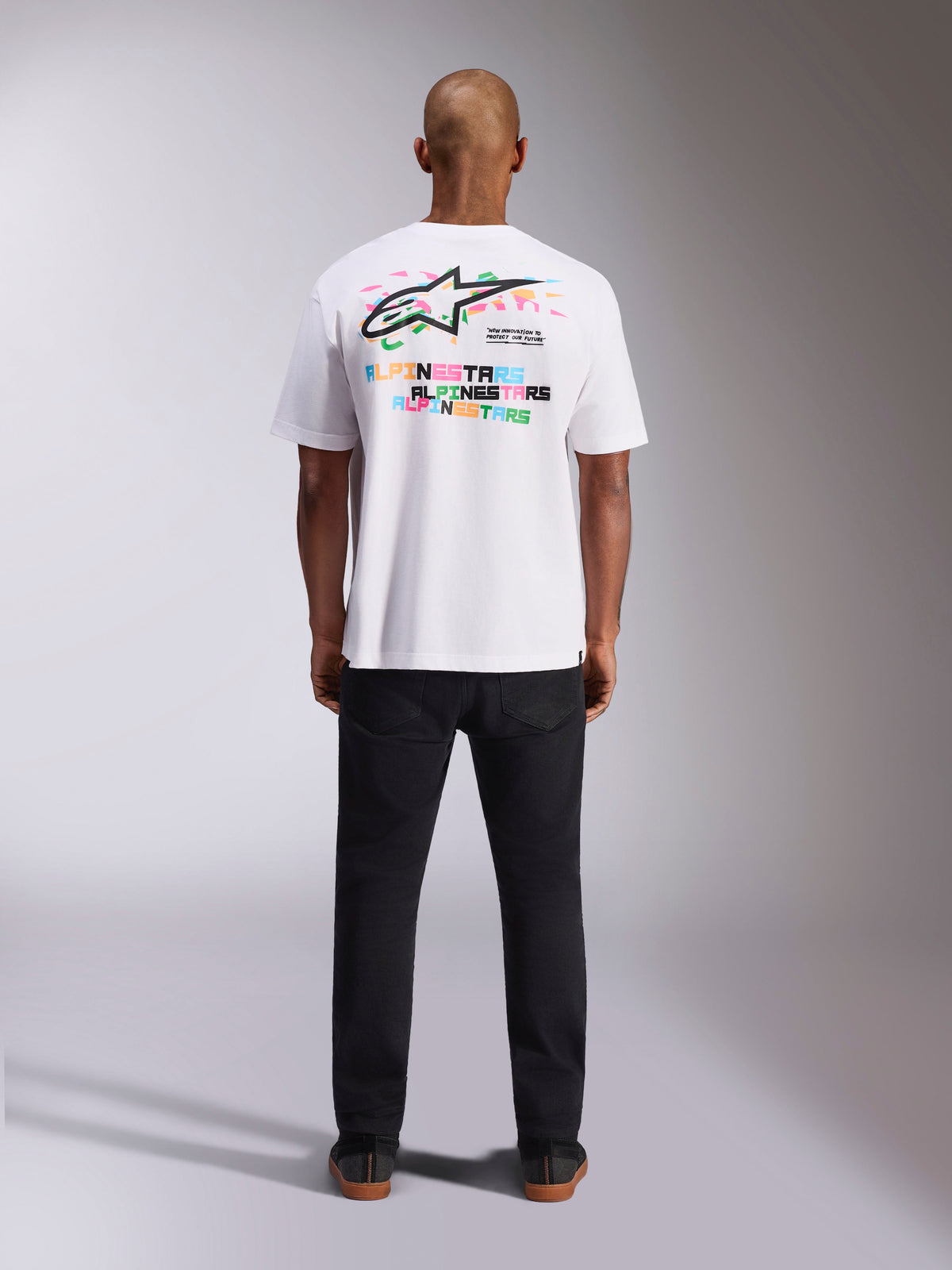 Alpinestars Wild Oversized CSF Tee, kortärmad t-shirt, vit, vy bakifrån som visar livfull flerfärgad Astars-logotyp och upprepad typografi, avslappnad motorsportinspirerad streetwear