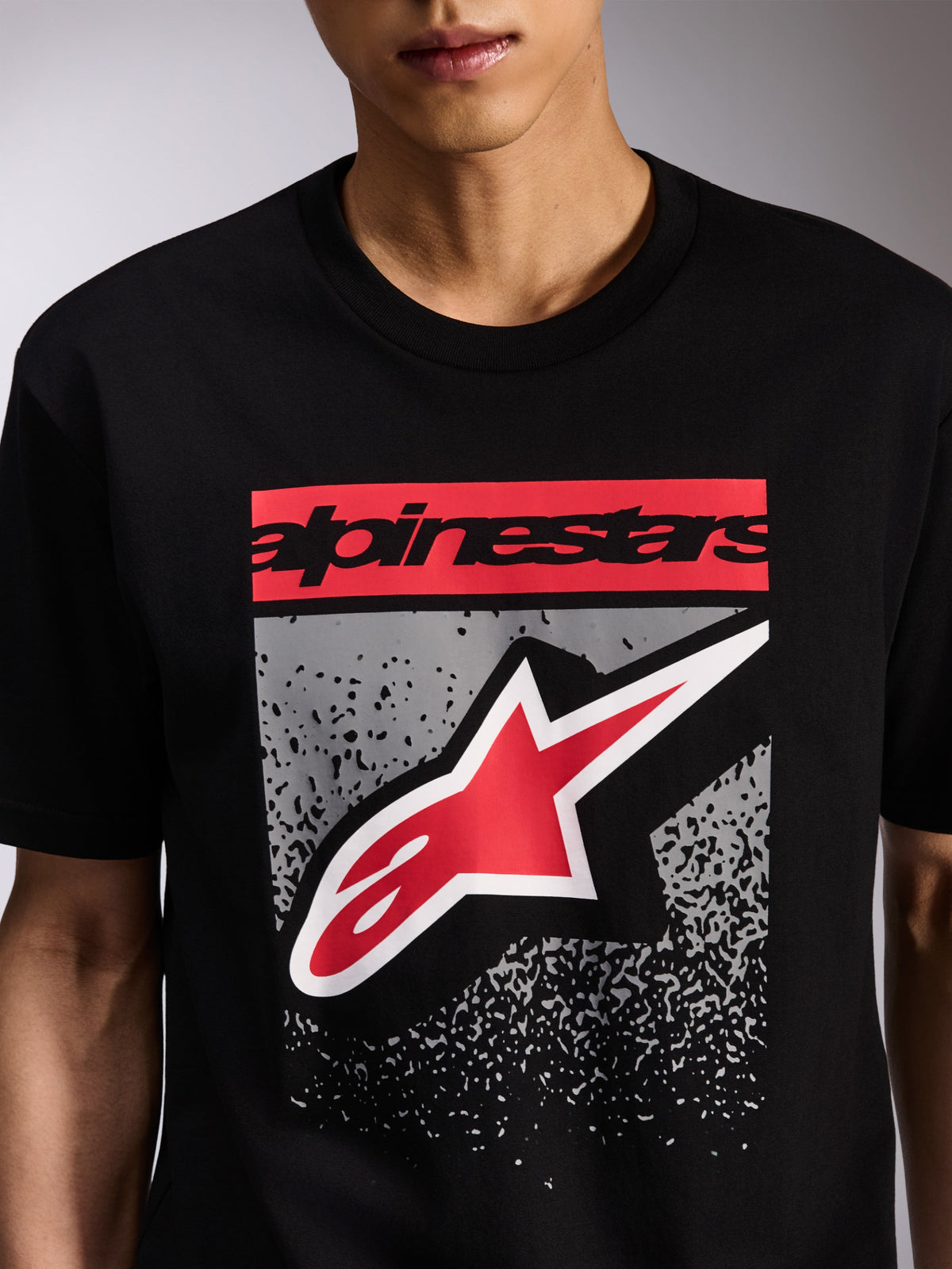 Alpinestars Noka CSF Tee, kortärmad t-shirt, svart, grafik på framsidan med röd Alpinestars-ordlogotyp och röd och vit Astars-logotyp på grå MX-övertoning, casual motorsport-streetwear