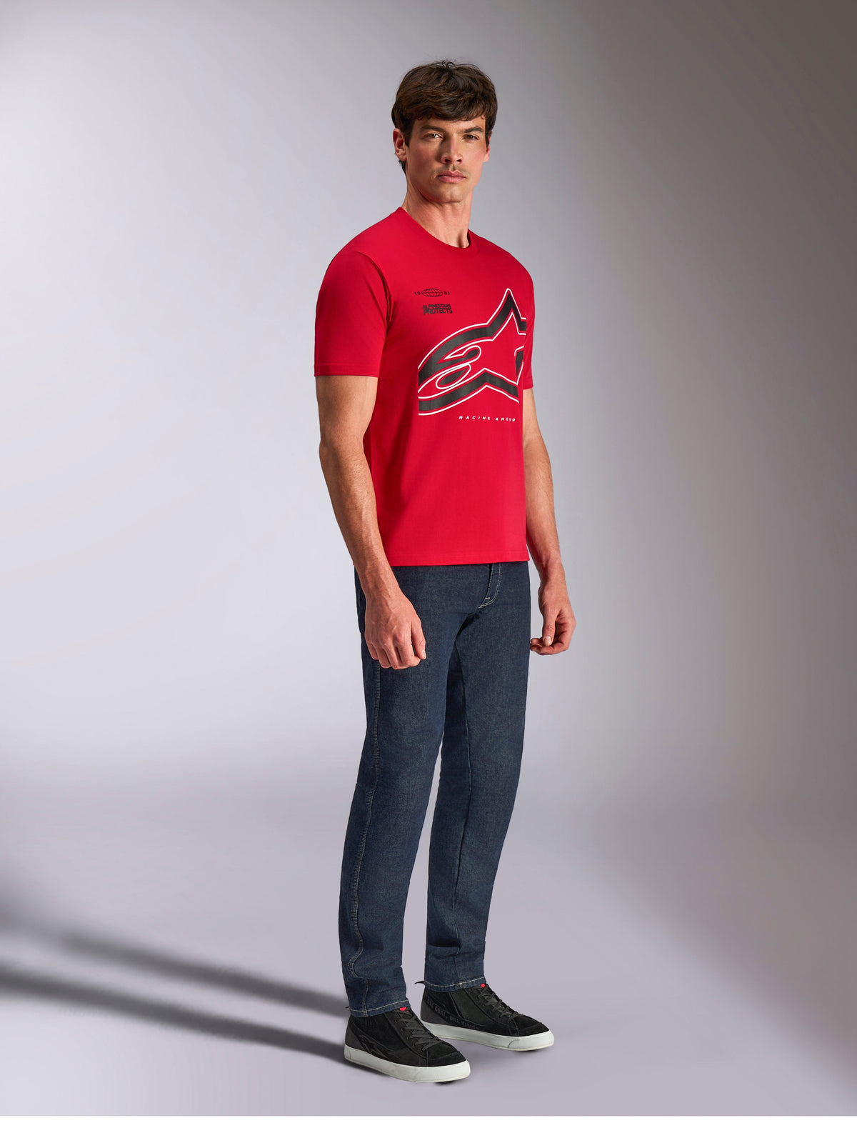 Alpinestars Authority CSF Tee, kortärmad t-shirt, röd, stor beskuren Astars-logotyp med svarta och vita konturer, bärs av modell med mörka jeans och svarta sneakers, avslappnat motorsport-inspirerat streetwear