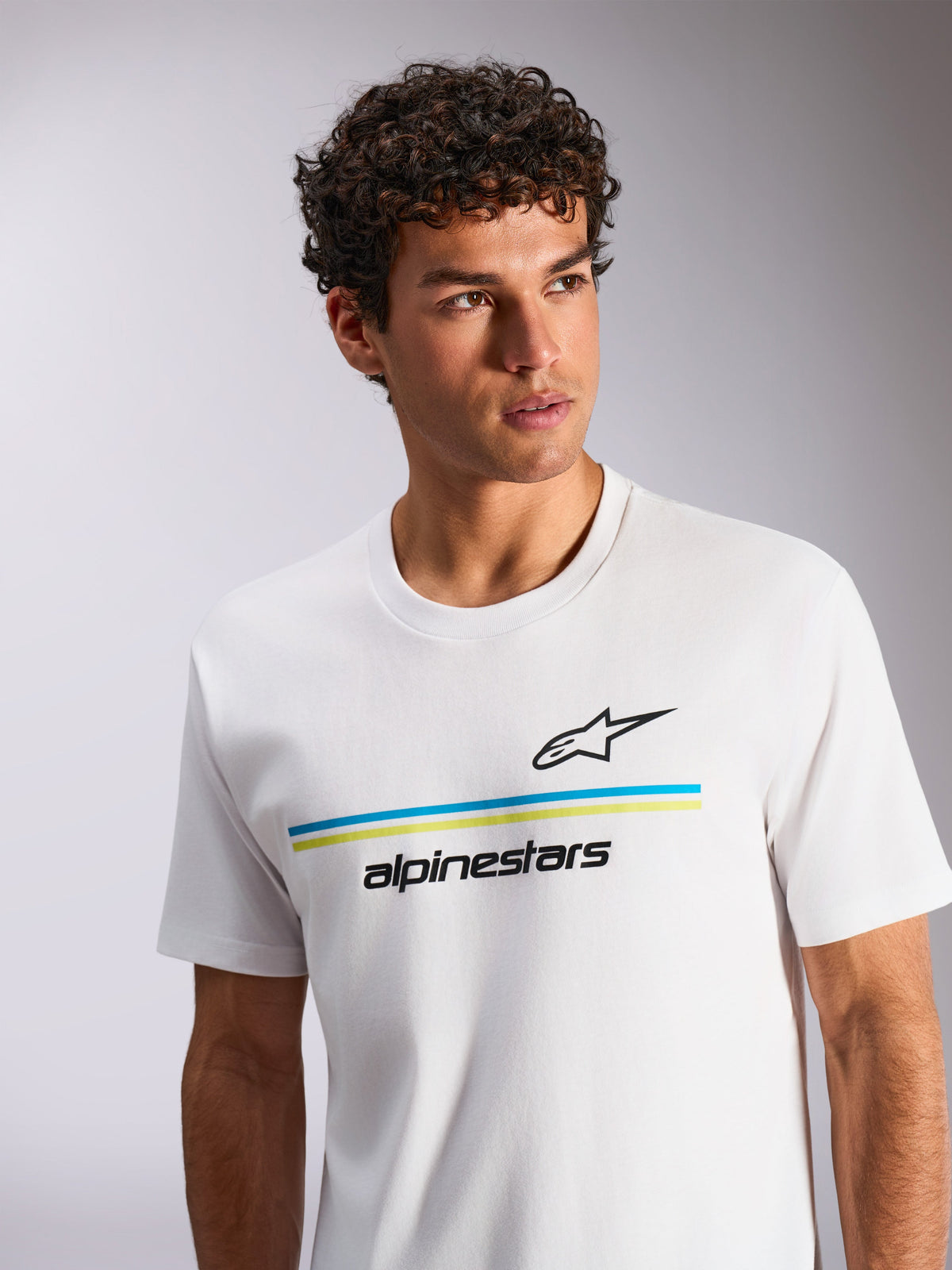 Alpinestars Lanes CSF Tee, Short Sleeve T-Shirt, White, featuring blue and lime green horizontal stripes with black Astars logo and wordmark, worn by a model with curly hair, casual motorsport-inspired streetwear
