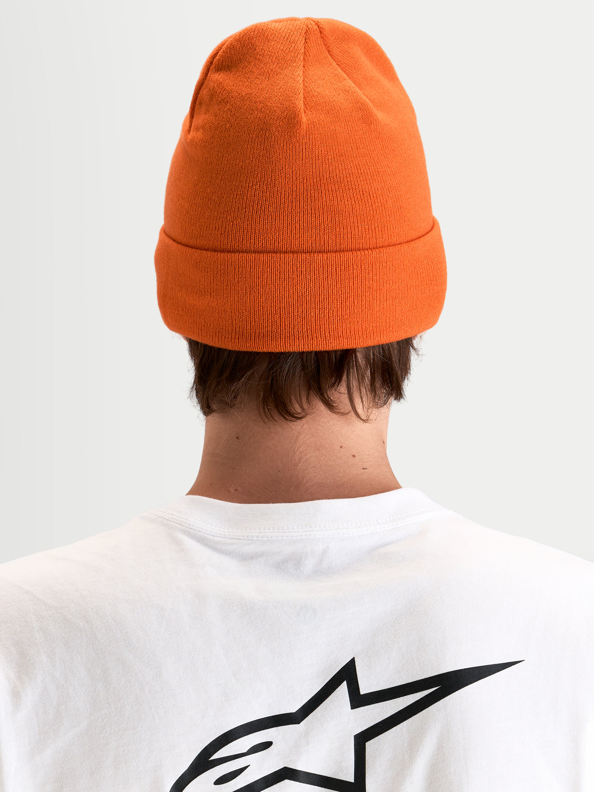 Alpinestars Augment Cuff mössa, orange stickad mössa med uppvikbar kant och djup passform, vy bakifrån på modell som bär vit t-shirt med svart Astar-logotyp