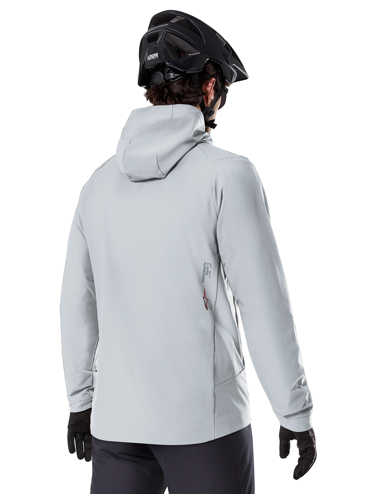 Alpinestars A-Dura Thermal Jacka, Titaniumgrå, vy bakifrån av en cyklist som bär den isolerade jackan med huva, kombinerad med en svart MTB-hjälm och svarta handskar, med en liten Alpinestars-logotyp på nedre delen av ryggen, designad för mountainbiking i kallt väder.