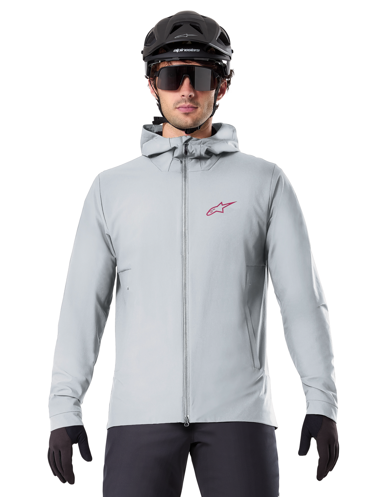 Alpinestars A-Dura Thermal Jacka i Titanium, ljusgrå cykeljacka med huva, röd stjärnlogotyp på bröstet, bärs av en cyklist med svart MTB-hjälm, solglasögon och handskar, isolerad utrustning för mountainbike