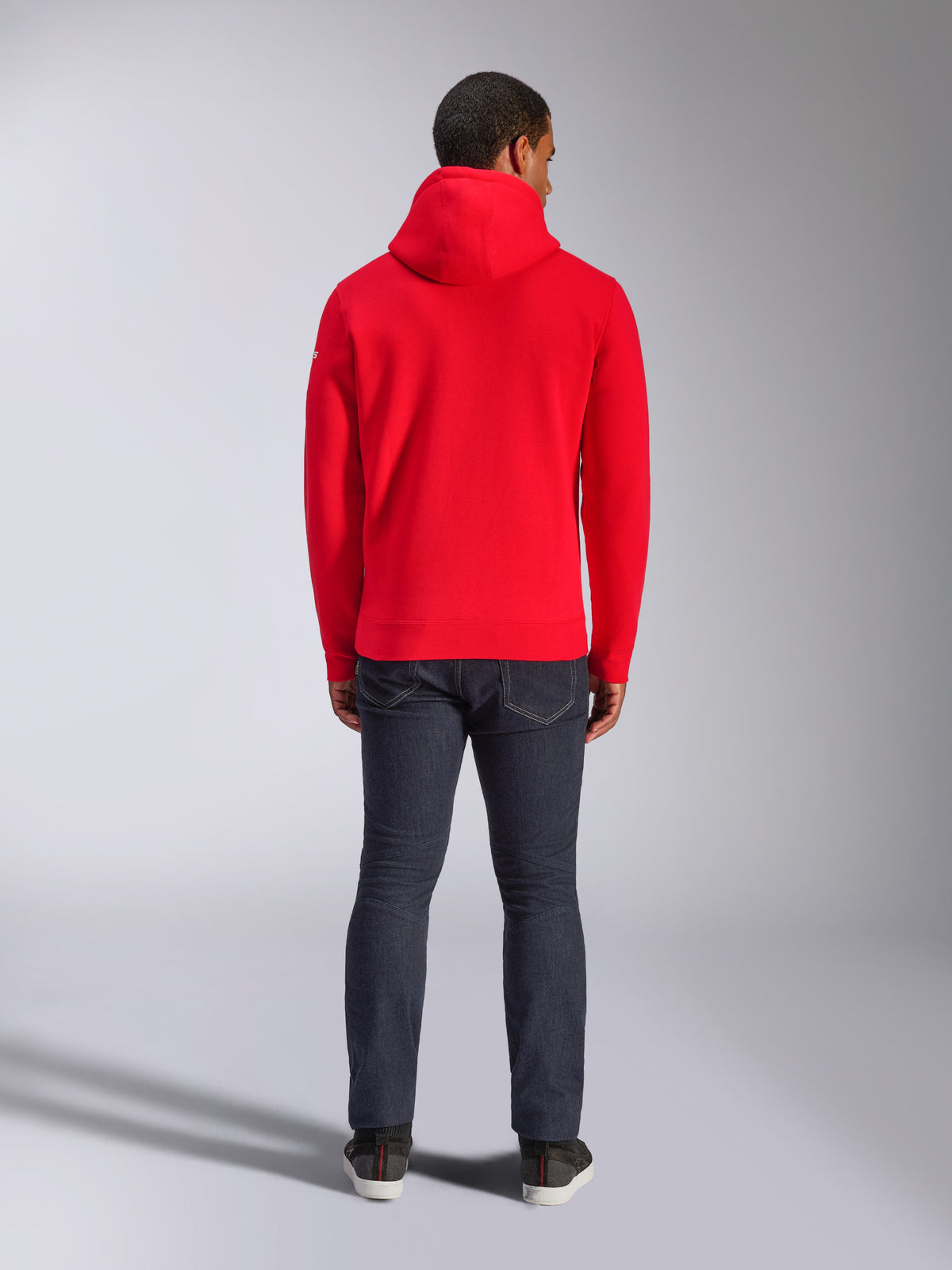 Alpinestars Frontal Hoodie, röd fleece-hoodie i pullover-modell, vy bakifrån, casual streetwear-stil, bärs med mörka denimjeans och sneakers, har huva och ribbad fåll