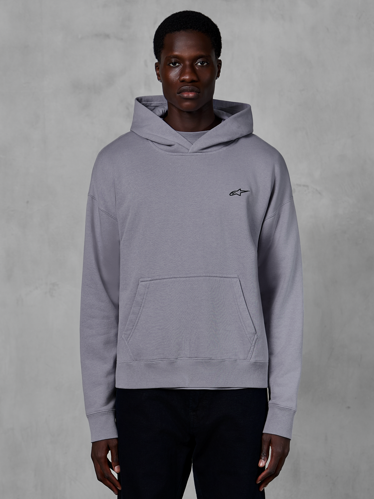 Alpinestars Essentials Ageless Hoodie, silvergrå huvtröja, vardaglig streetwear, med en liten svart Astars-logotyp på bröstet, känguruficka framtill, huva med omlottringning och mjuk stentvättad finish.