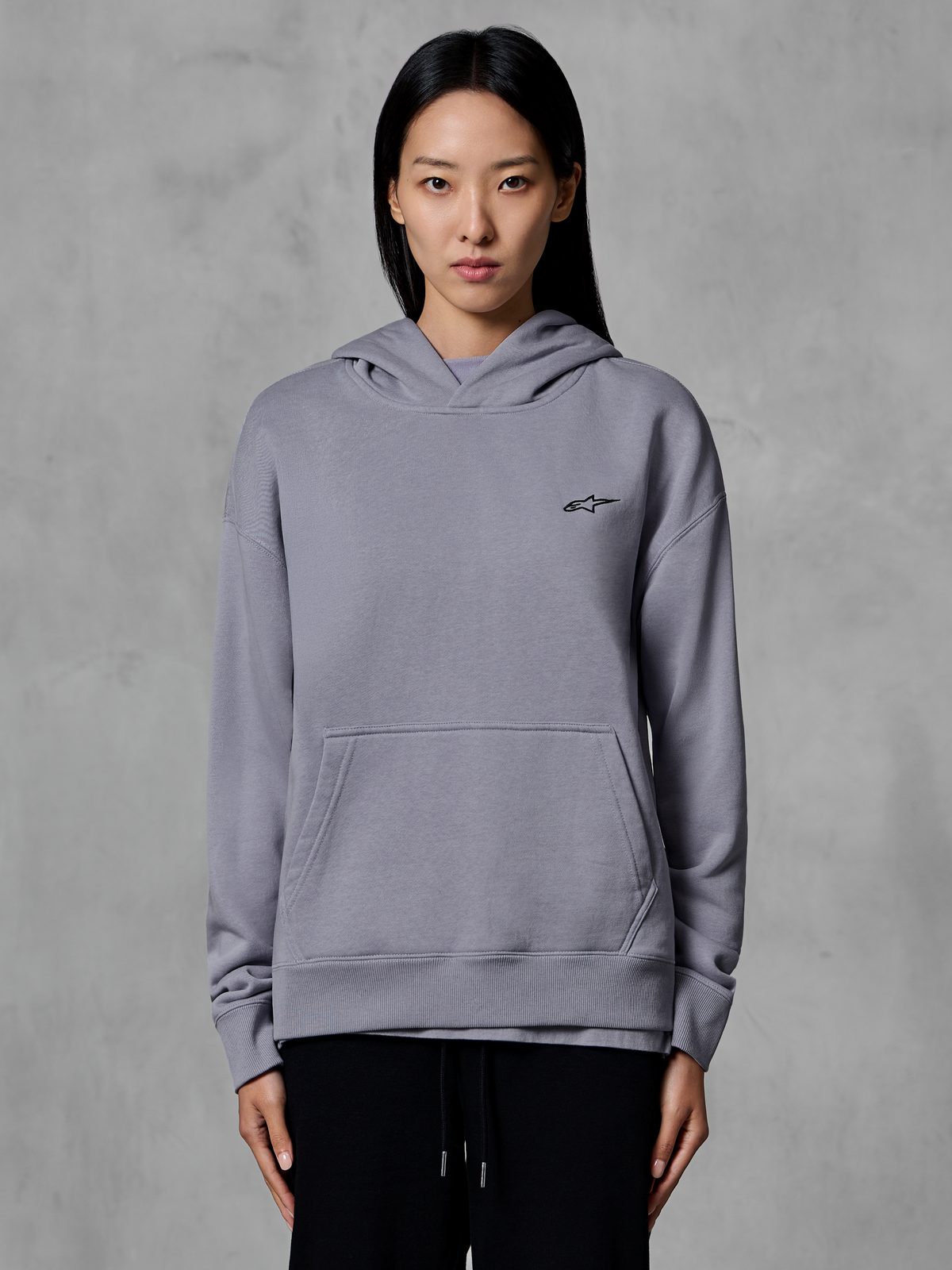 Alpinestars Essentials Ageless Hoodie, vardagliga sportkläder, silverfärgad med en liten svart logotyp, känguruficka, huvtröja buren av modell, moderna livsstilskläder