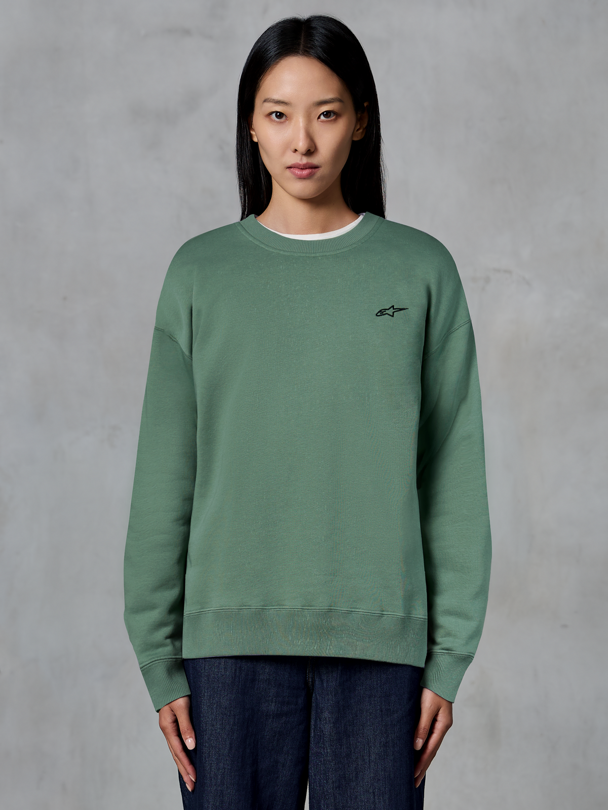 Alpinestars Essentials Ageless Crew, crewneck-tröja, kaktusgrön, bärs av en modell, liten svart logotyp på bröstet, ribbad krage, muddar och fåll, avslappnad motorsport-streetwear