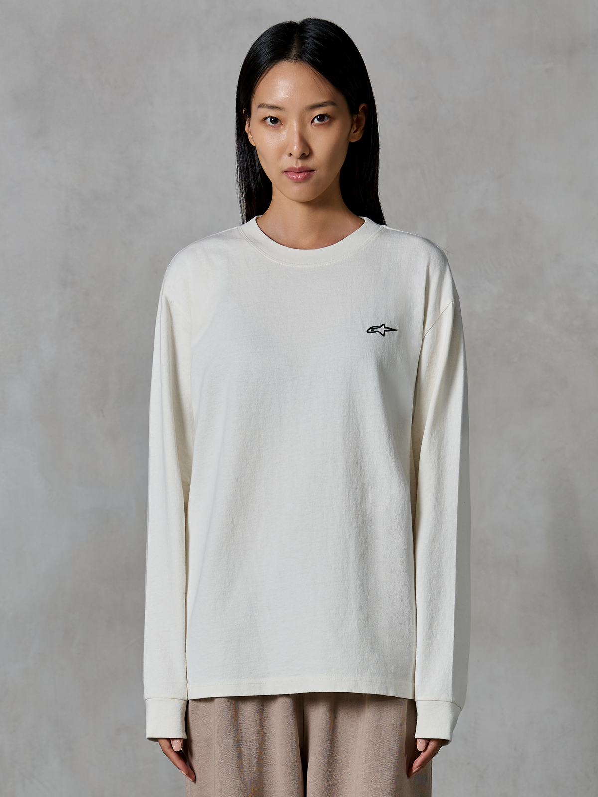 Alpinestars Essentials Ageless LS Tee, långärmad t-shirt, off-white, med en liten svart stjärnlogotyp på bröstet, avslappnad modern passform, ekologisk bomullsjersey, avslappnad motorsportinspirerad streetwear