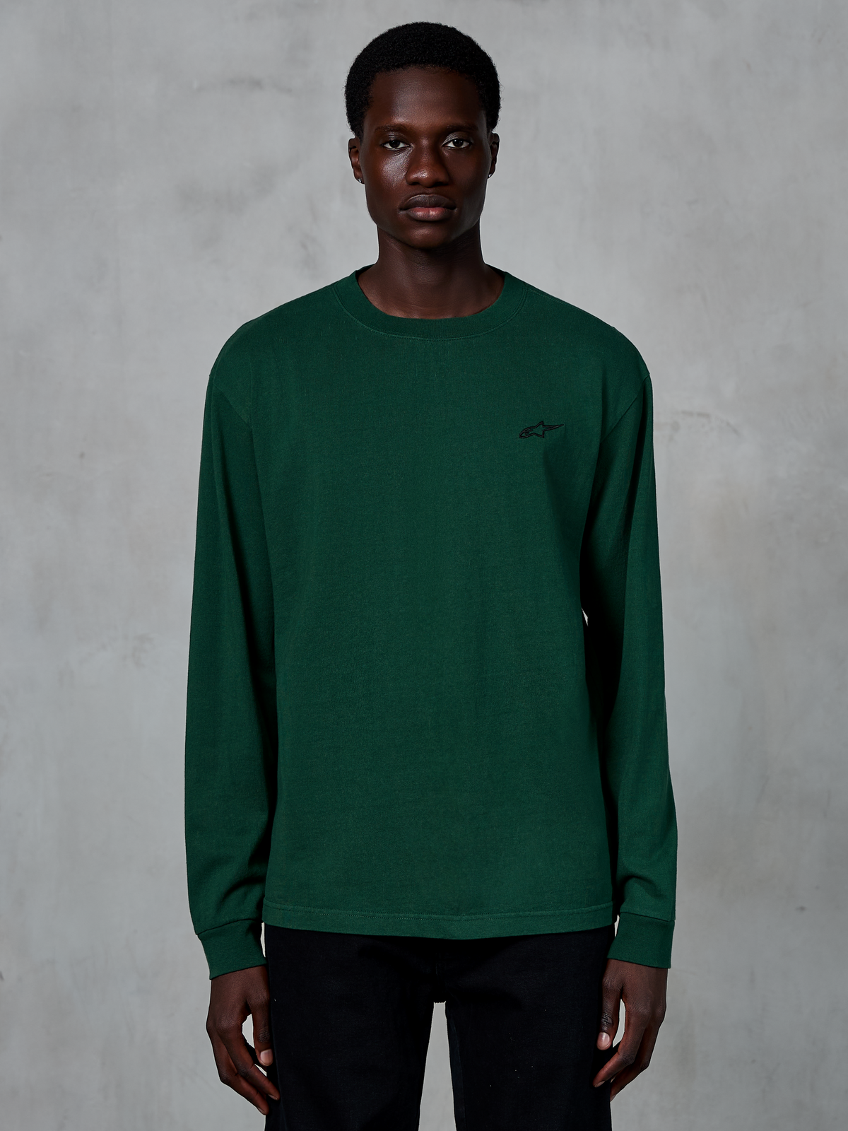Alpinestars Essentials Ageless LS Tee, långärmad t-shirt, tallgrön, buren av modell, liten svart logotyp på bröstet, avslappnad streetwear, 100 % ekologisk bomull med stentvättad finish
