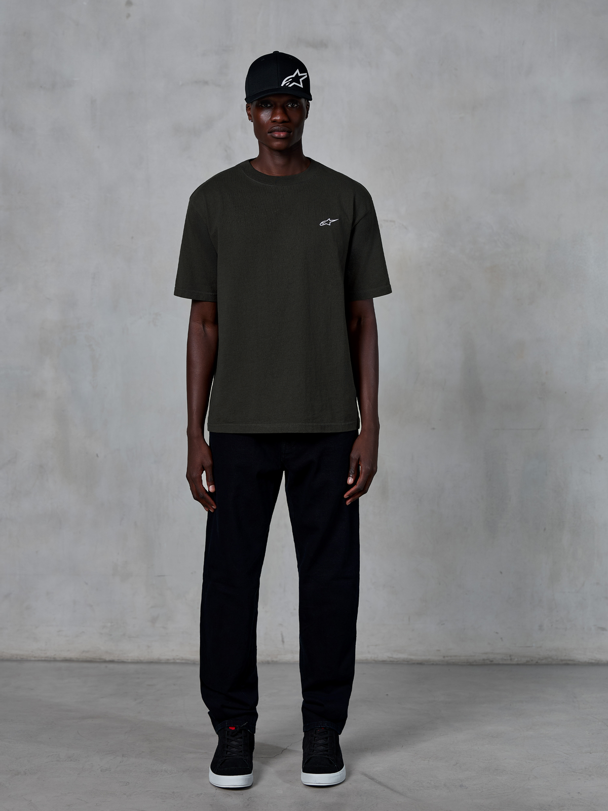 Alpinestars Essentials Ageless SS Tee, kortärmad t-shirt, Off Black, med en liten vit Alpinestars-logotyp på bröstet, buren av en modell med svart keps och byxor för en ren lifestyle-look