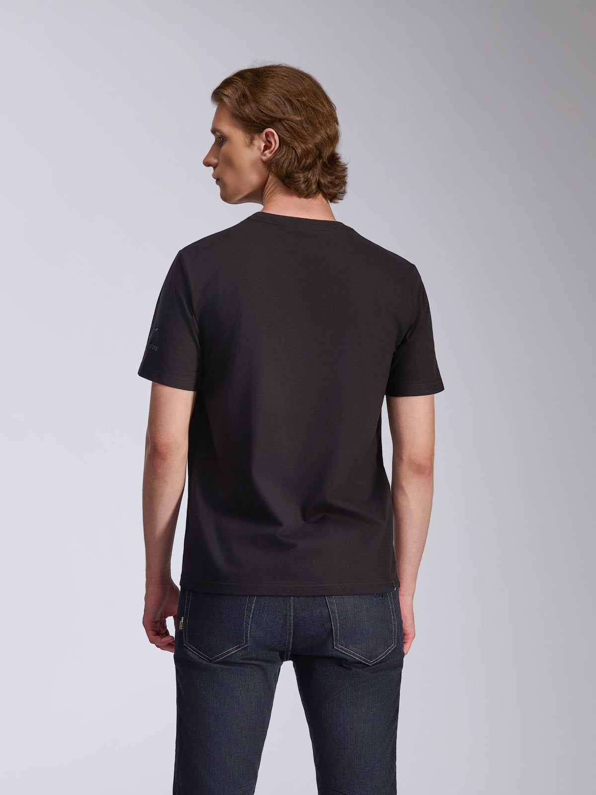 Alpinestars Global CSF T-shirt, kortärmad t-shirt, svart, baksida sedd på en modell, kombinerad med mörkblå jeans, avslappnad motorsport-streetwear