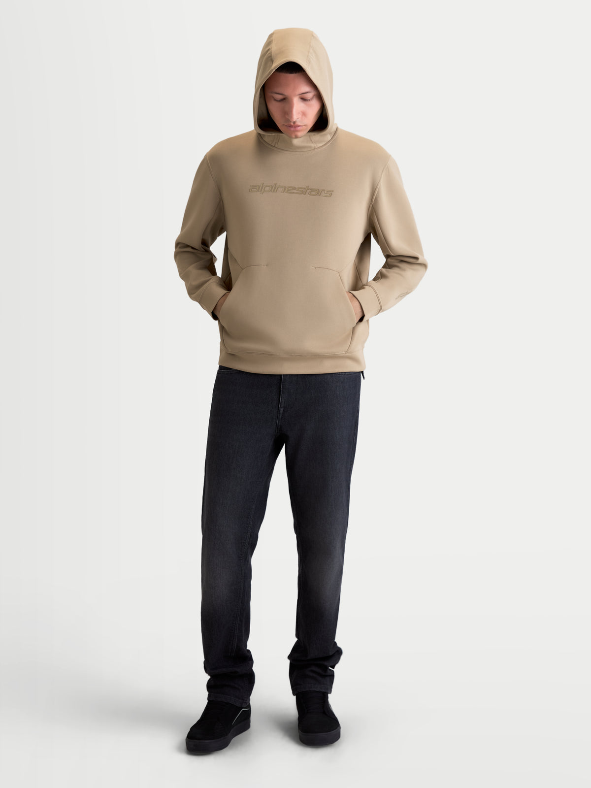 Alpinestars Datrix huvtröja, beige herrhuvtröja för sportswear, mjuk dubbelvävd fleece med meshfodrad huva, tonad HD-logotyp på bröstet och ficka med dartdetalj, modellen bär huvan uppe.