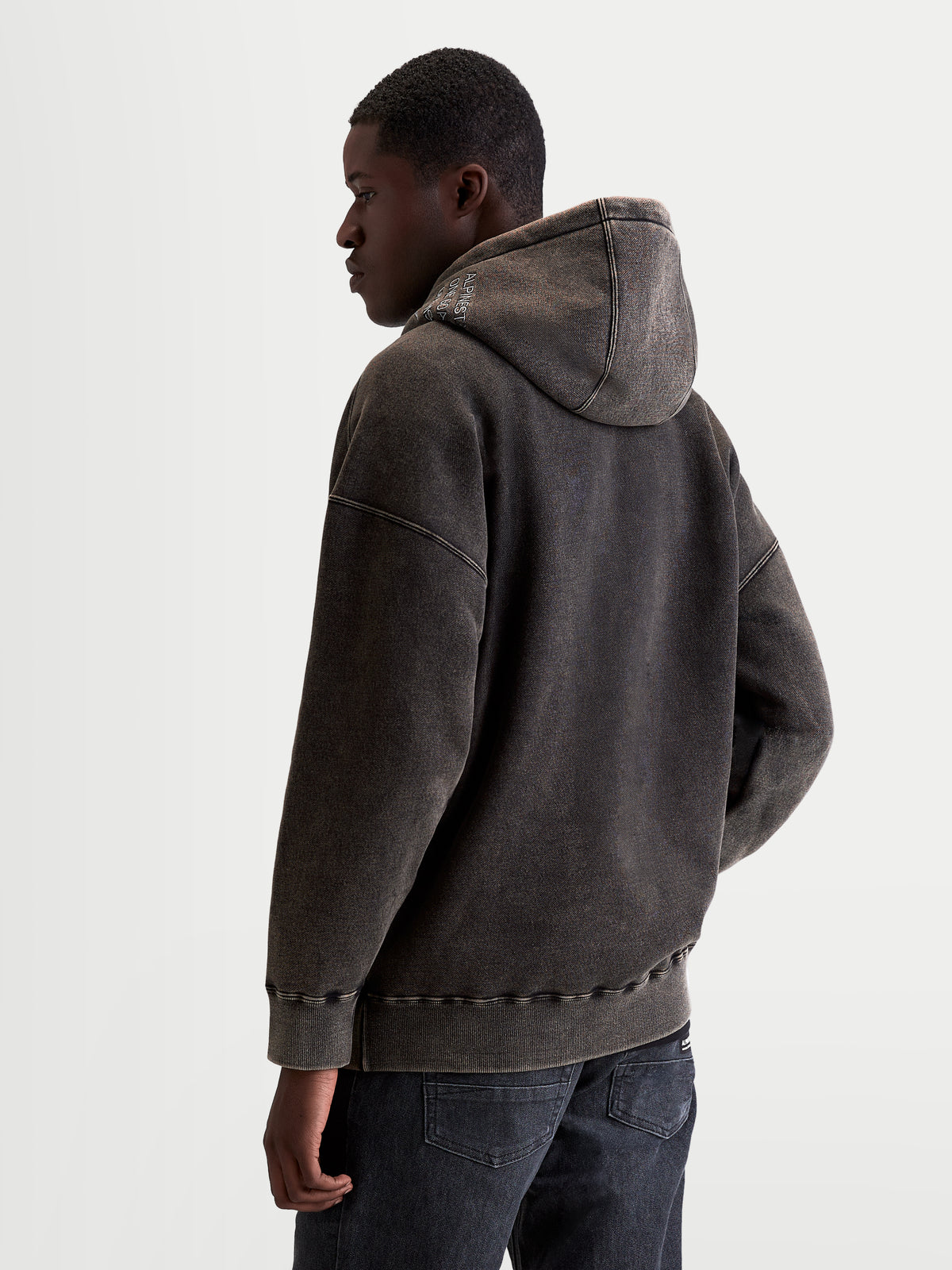 Alpinestars Infinite Washed Oversize huvtröja, oversized huvtröja för herrar i svart fleece med snötvättad finish, ryggvy på modell, broderad logotyp på huvan, avslappnad passform, sportswear.