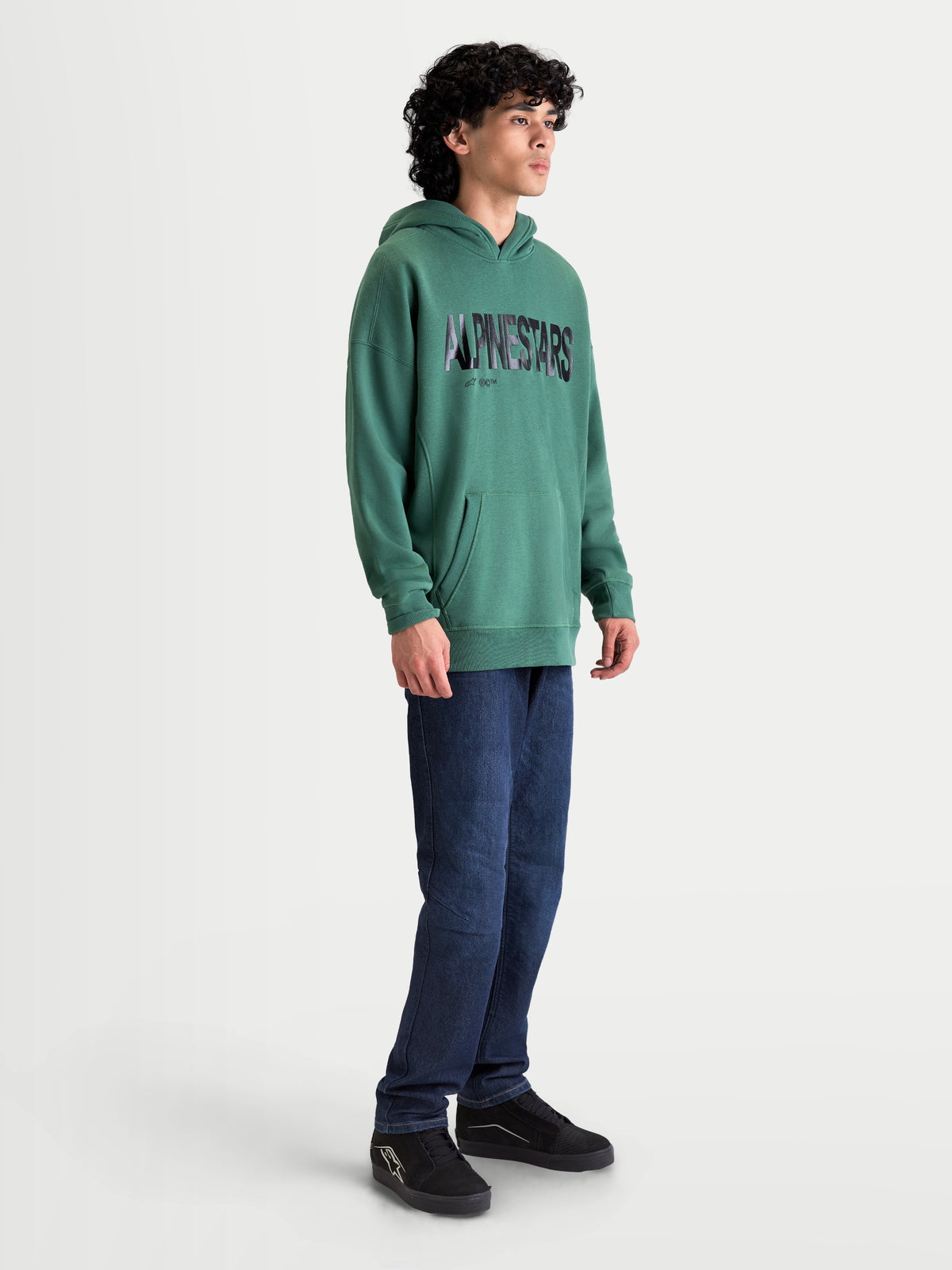 Alpinestars Shaw oversized huvtröja, grön sportswear-huvtröja med texturerad Alpinestars-logotyp, känguruficka och avslappnad oversized passform i mjuk bomulls- och polyesterfleece, visas på modell