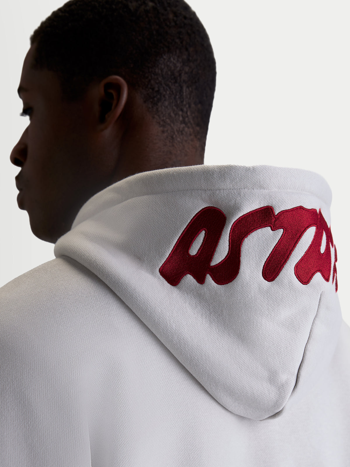 Alpinestars Pioneer Oversized Hoodie, Casual Sportswear Fleece for Men and Women, Cement Gray with Red embroidered logo on the hood, on-model back view highlighting the oversized fit and premium branding.