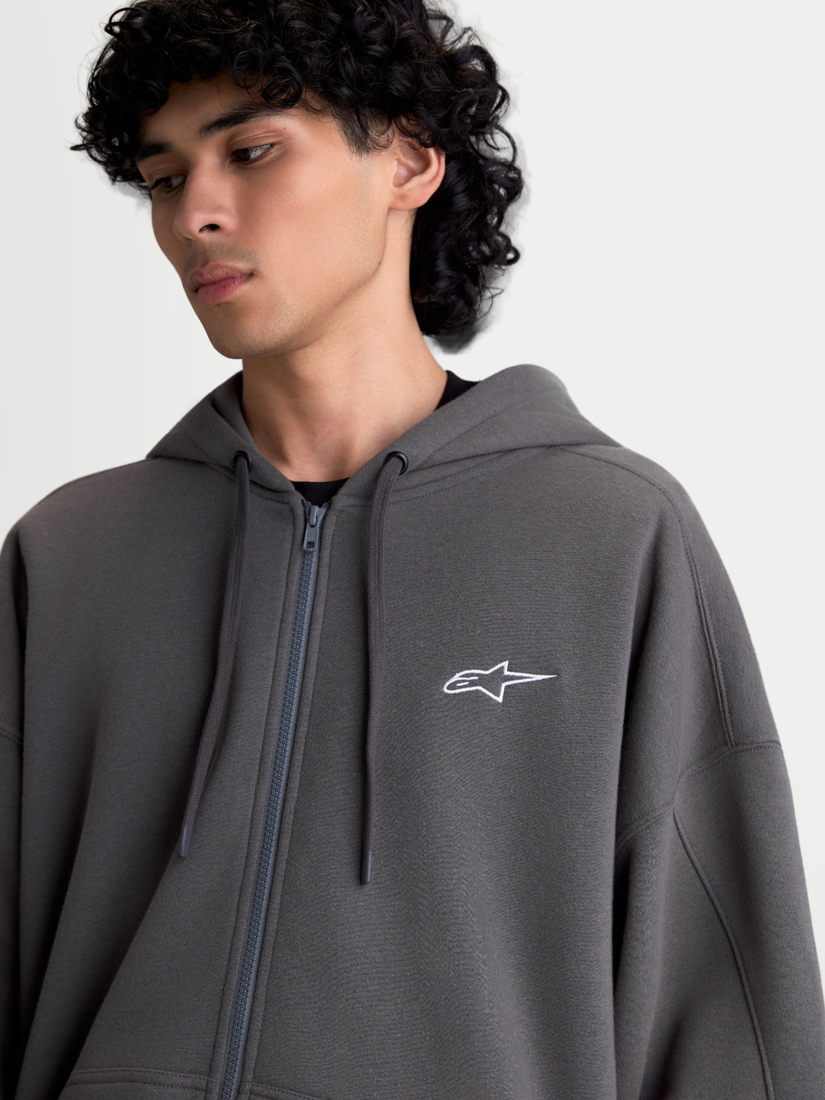 Alpinestars Entity Oversized huvtröja, mörkgrå fleecehuvtröja med dragkedja, broderad vit Astars-logotyp på bröstet, avslappnad oversized passform, Vislon-dragkedja och platta dragskor.