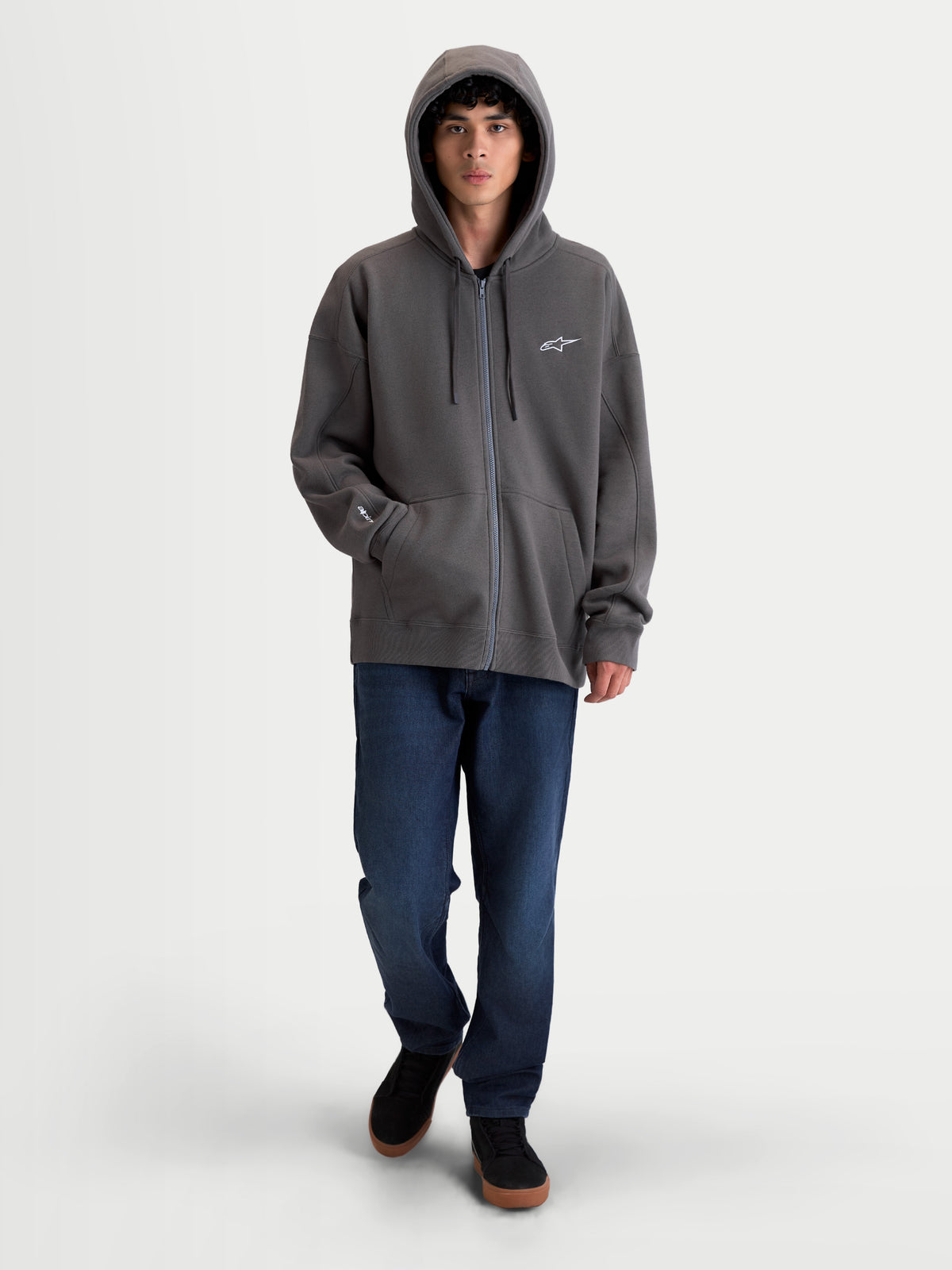 Alpinestars Entity Oversized huvtröja, mörkgrå fleecehuvtröja med dragkedja, premium motorsport-sportswear, känguruficka och broderad Astars-logotyp på bröstet, på modell med avslappnad oversized siluett