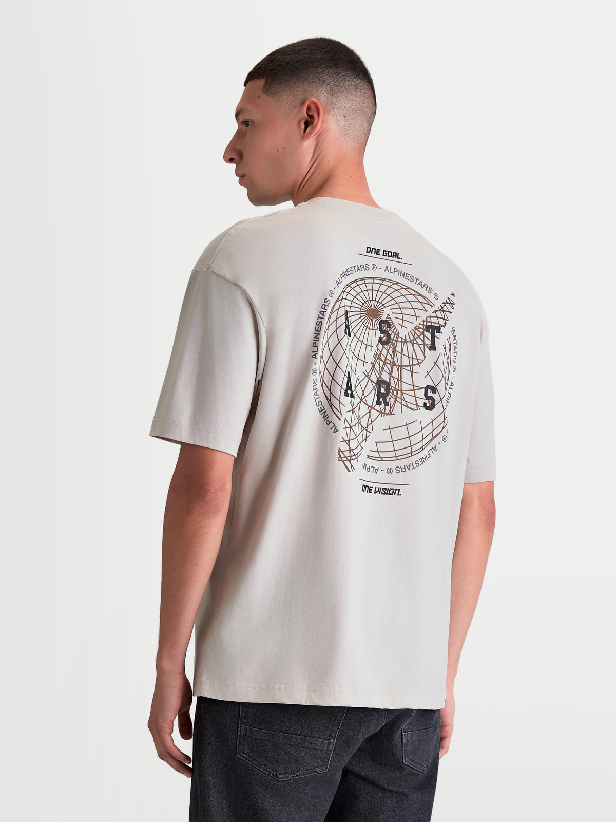 Alpinestars Latitude Oversized CSF t-shirt, kortärmad herrt-shirt för vardagsbruk, cementgrå, stor globgrafik på ryggen med ASTARS-ordmärke och One Goal One Vision-mottot, oversized passform, bomulls-polyesterblandning.