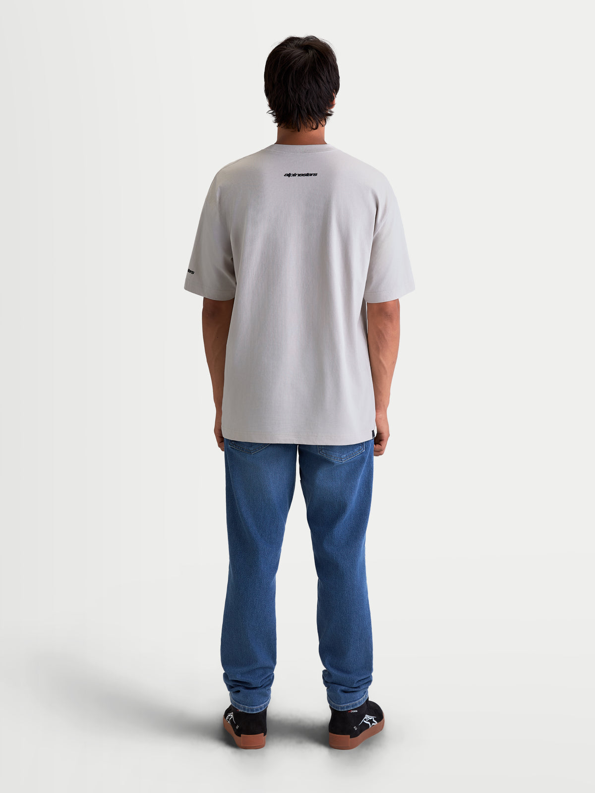 Alpinestars Mandate Oversized CSF t-shirt, kortärmad sportswear-t-shirt i unisex-modell, grå, mjuk bomullsblandning, bakifrån på modell med svart Alpinestars-logotyp på övre ryggen.