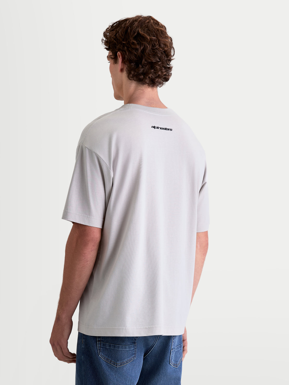 Alpinestars Prelude Oversized CSF t-shirt, kortärmad sportswear-tröja i grått, oversized passform, mjuk bomulls- och polyesterblandning, liten svart Alpinestars-logotyp på ryggen, modell sett bakifrån