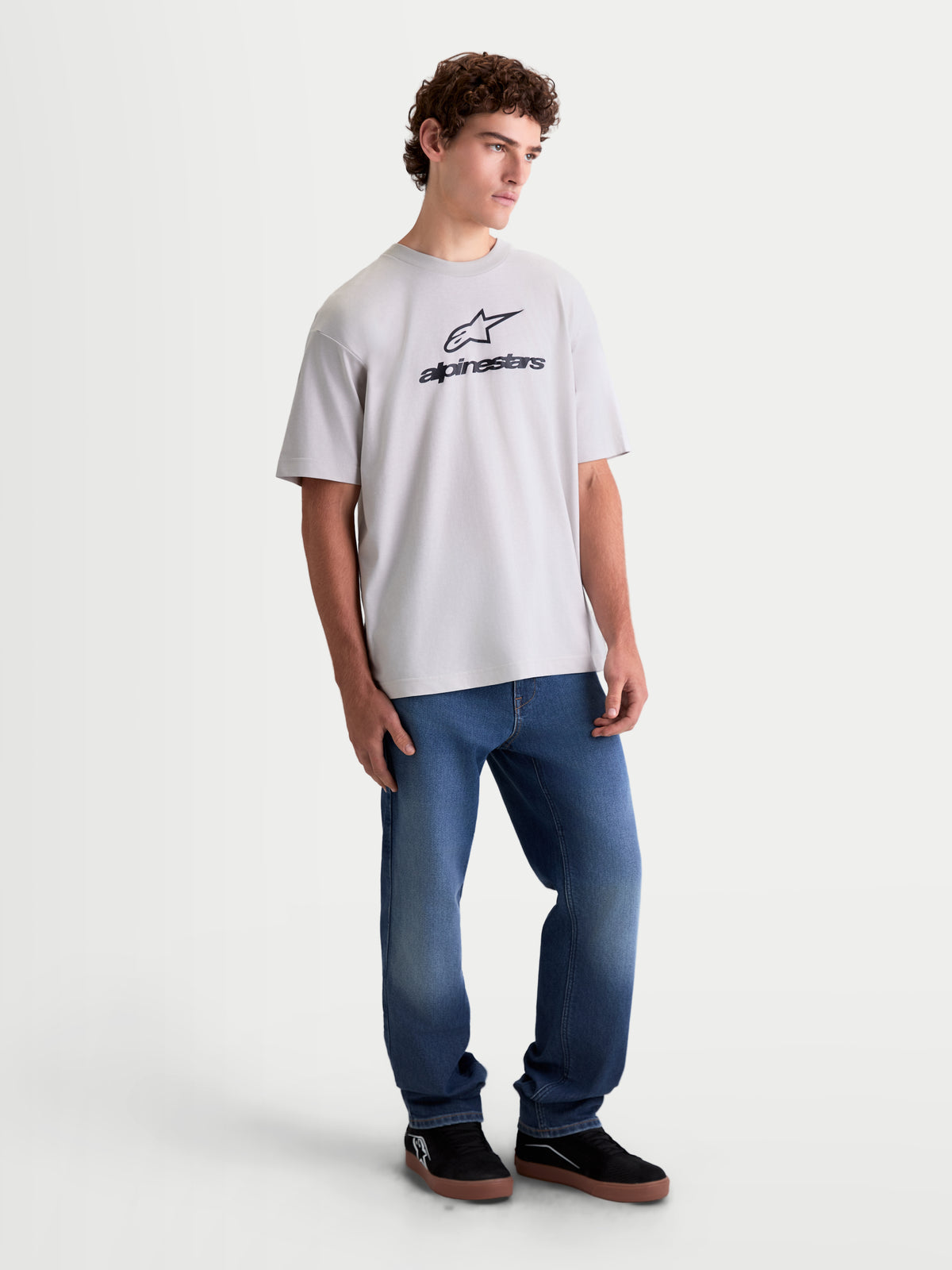 Alpinestars Prelude Oversized CSF t-shirt, kortärmad sportswear-t-shirt på modell, cementgrå med svart staplad Astars-logotyp på bröstet, avslappnad oversized-passform i bomulls- och polyesterblandning för vardagskomfort